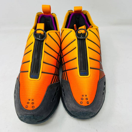 The Nike Air Max Sunder SP Kids of Immigrants Sunrise sneakers in bright orange and black feature a grid pattern with blue accents. An authentic swoosh and a circular K-I design mark the shoes and the orange box, highlighting their uniqueness.