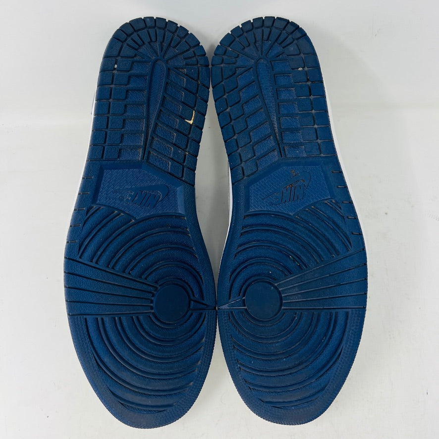 The Jordan 1 Low SB Midnight Navy sneakers, with white and navy panels and a side Nike swoosh, are displayed on a pristine shoebox. A spare set of white laces featuring the Nike SB logo in Metallic Silver is also included.