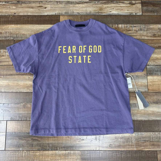 Fear of God Essentials Heavy Crewneck Tee in Lavender on wooden floor.