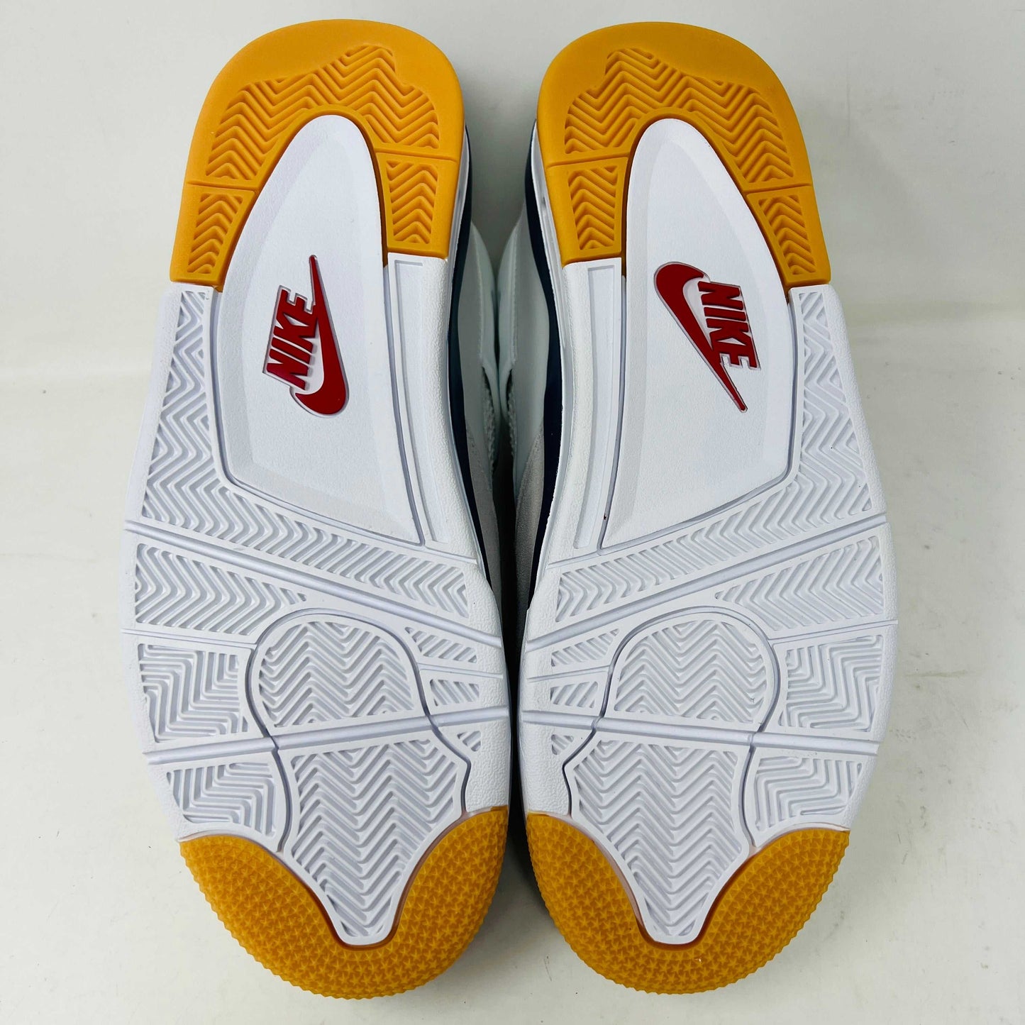 The Jordan 4 Retro SB Navy from Holy Ground Sneaker Shop, with white and navy mesh and orange details, sits on a pristine box showcasing the Nike SB logo. Its cushioned heel ensures its a perfect accessory addition.