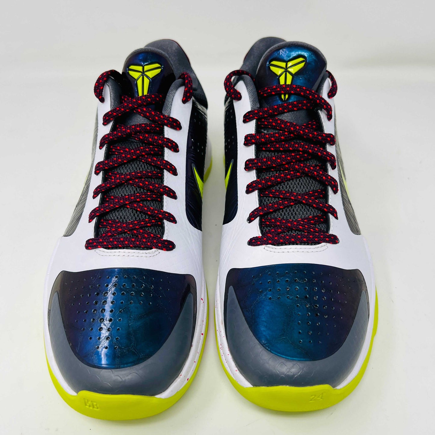 The Nike Kobe 5 Protro Chaos sneaker features a white and purple upper, neon yellow swoosh, maroon laces, and a neon yellow sole with red speckles. It is brand new in its sleek black box.