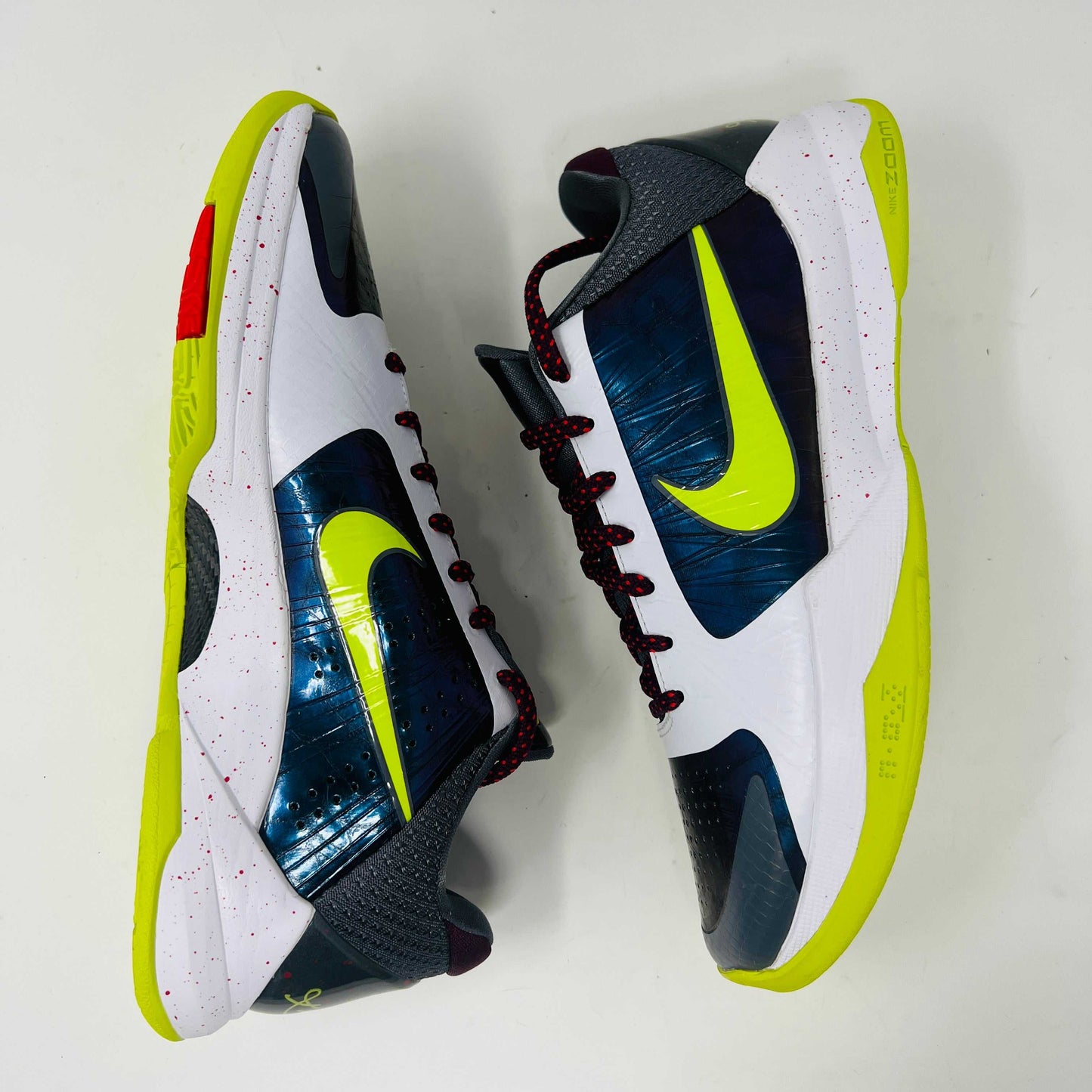 The Nike Kobe 5 Protro Chaos sneaker features a white and purple upper, neon yellow swoosh, maroon laces, and a neon yellow sole with red speckles. It is brand new in its sleek black box.