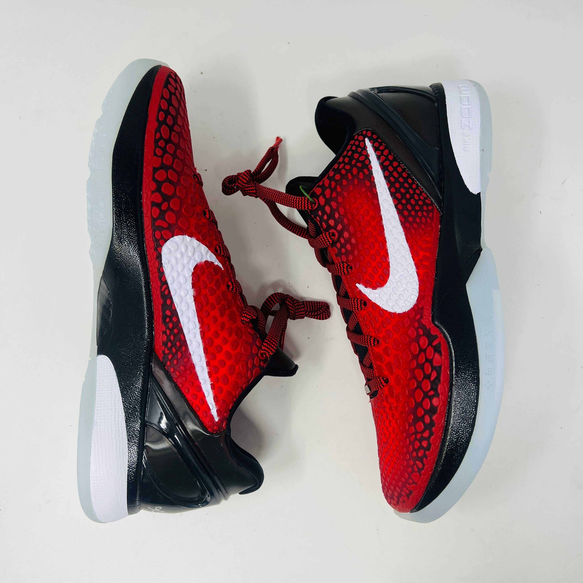 A brand new Kobe Nike Kobe 6 Protro Challenge Red All-Star (2021) sneaker, with a textured pattern and white swoosh, is showcased on a black shoebox. The authentic shoe has a black and white sole, red laces, and ZOOM on the side of the sole.