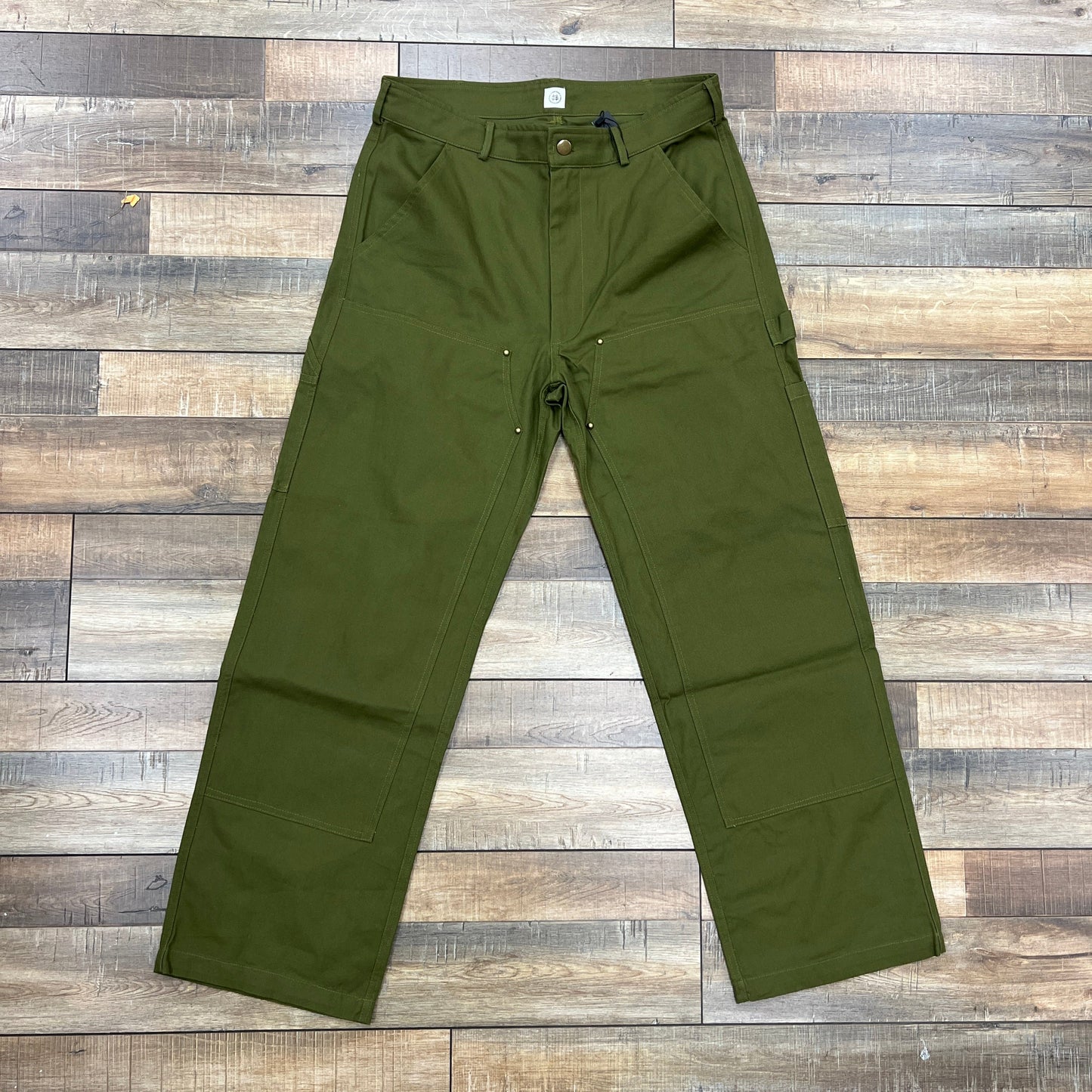 HG Double-Knee Pants in olive green on wooden floor, showcasing durable double-knee design.