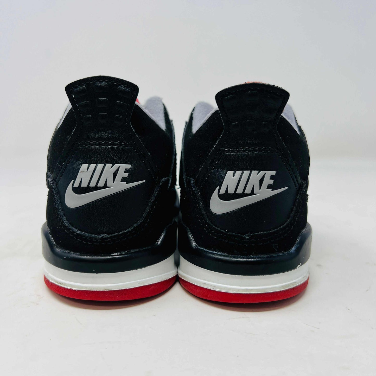 The Jordan 4 Retro Bred (2019) (PS) in black and red, featuring clean uppers with a white midsole and gray accents, sits on its original black shoebox. The box displays size, product details, and the iconic Jumpman logo, underscoring these authentic shoes from Jordans 2019 collection.