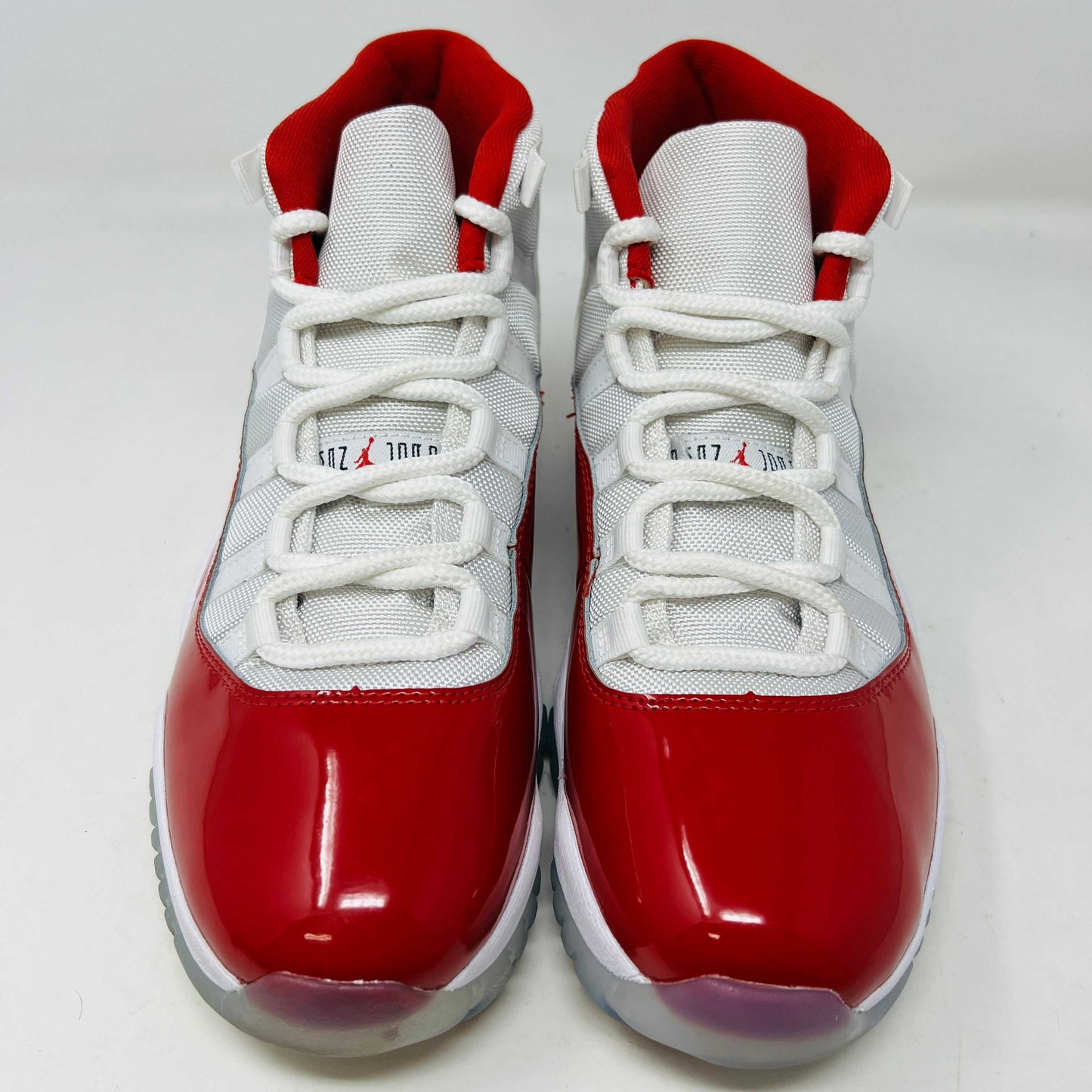 The Jordan 11 Retro Cherry (2022) is a red and white high-top sneaker with glossy red patent leather on the toe, clean mesh uppers, striking red accents, pristine white laces, a visible air sole unit, and the authentic Jumpman logo. Its in impeccable condition after being worn once.