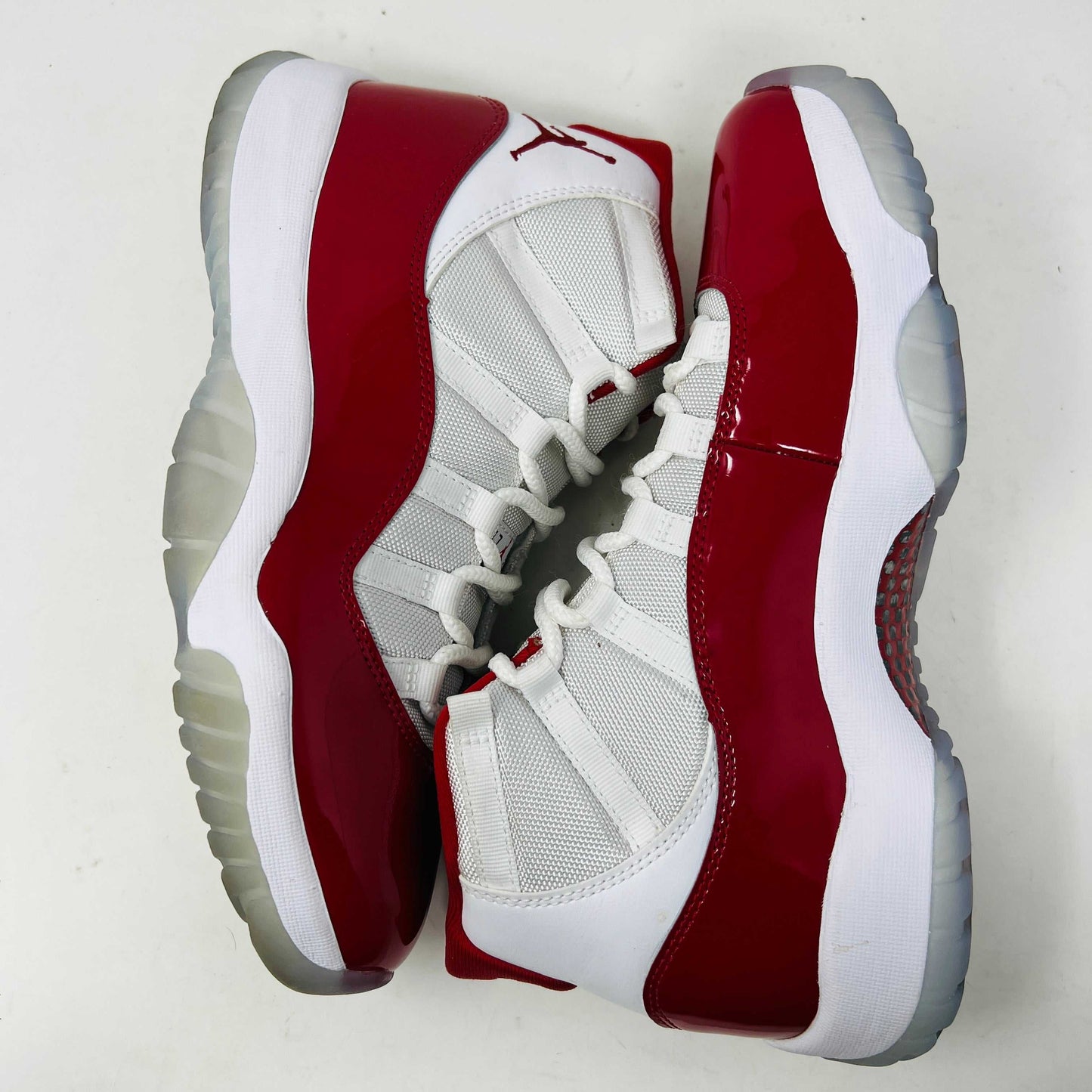 The Jordan 11 Retro Cherry (2022) is a red and white high-top sneaker with glossy red patent leather on the toe, clean mesh uppers, striking red accents, pristine white laces, a visible air sole unit, and the authentic Jumpman logo. Its in impeccable condition after being worn once.