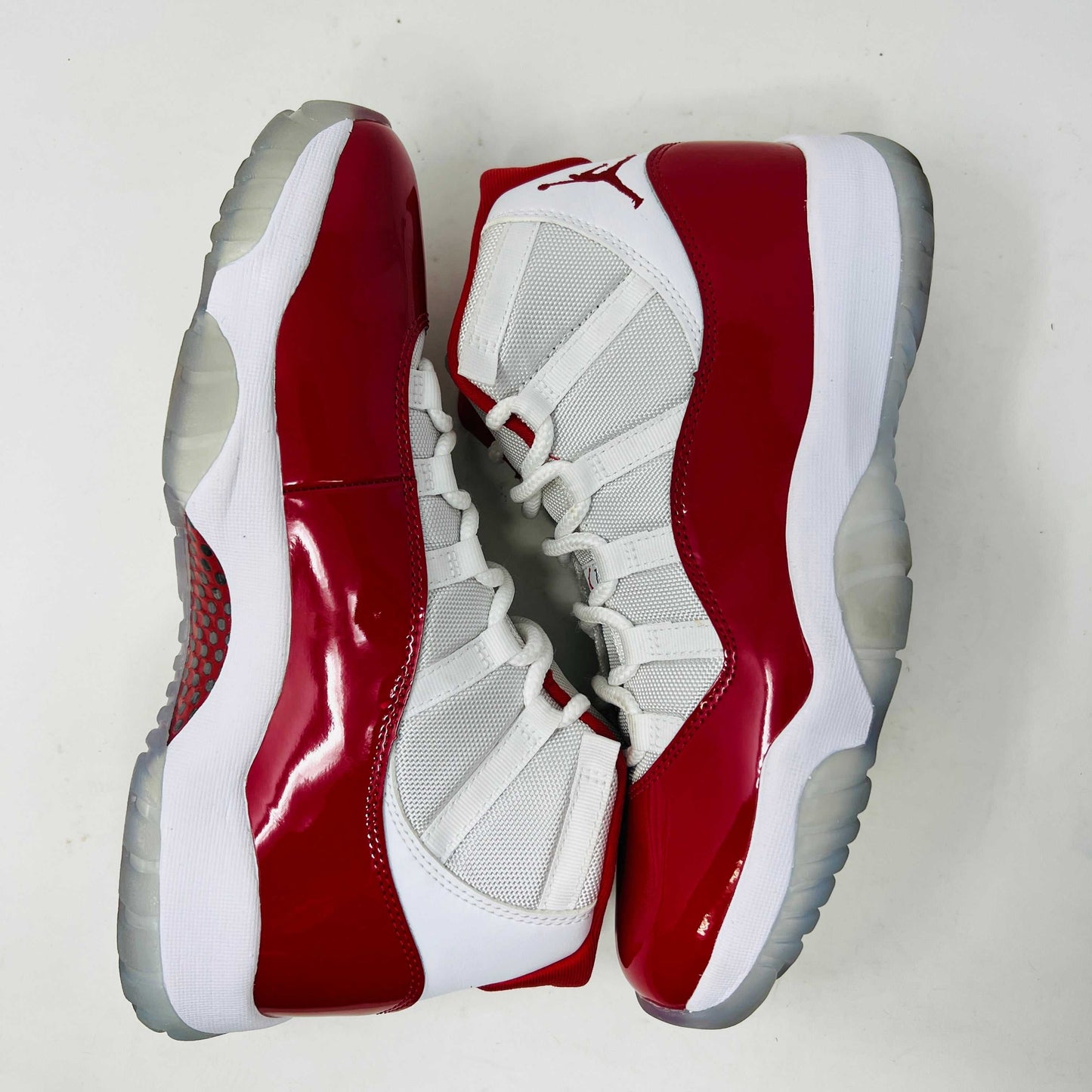 The Jordan 11 Retro Cherry (2022) is a red and white high-top sneaker with glossy red patent leather on the toe, clean mesh uppers, striking red accents, pristine white laces, a visible air sole unit, and the authentic Jumpman logo. Its in impeccable condition after being worn once.