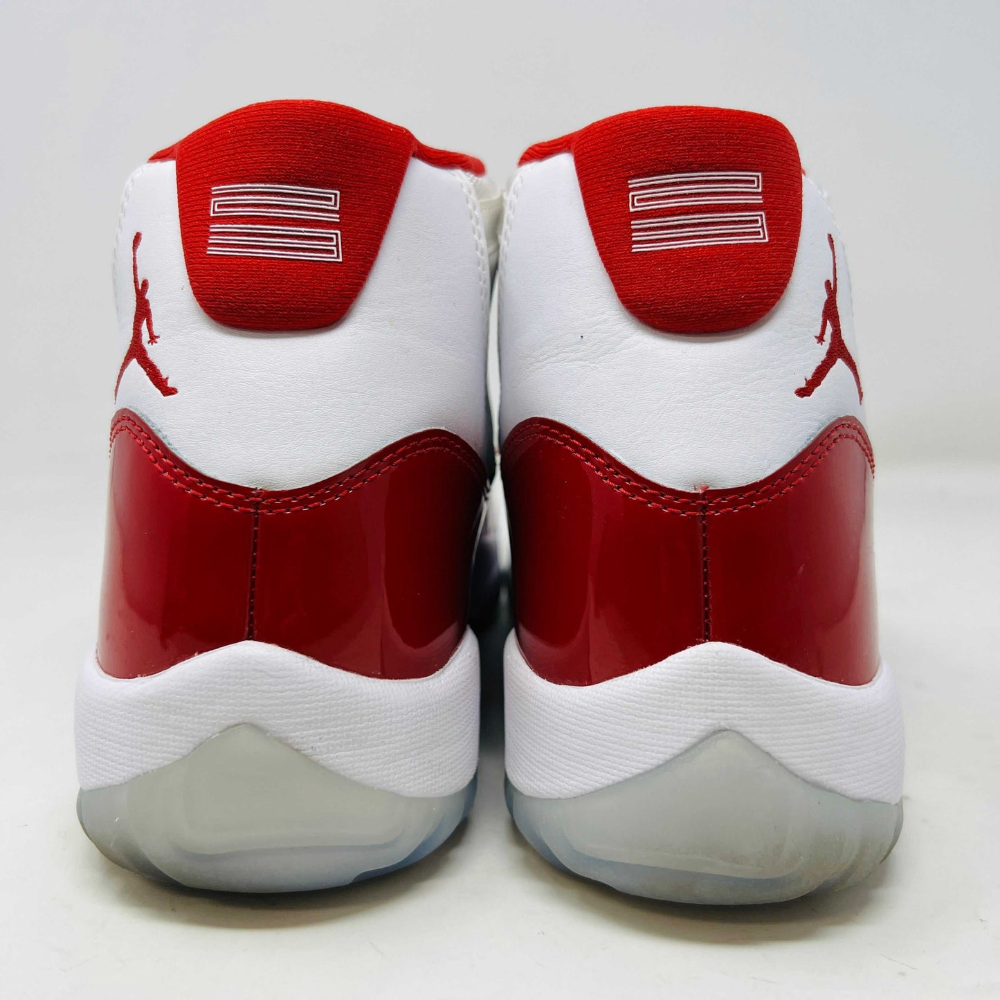 The Jordan 11 Retro Cherry (2022) is a red and white high-top sneaker with glossy red patent leather on the toe, clean mesh uppers, striking red accents, pristine white laces, a visible air sole unit, and the authentic Jumpman logo. Its in impeccable condition after being worn once.