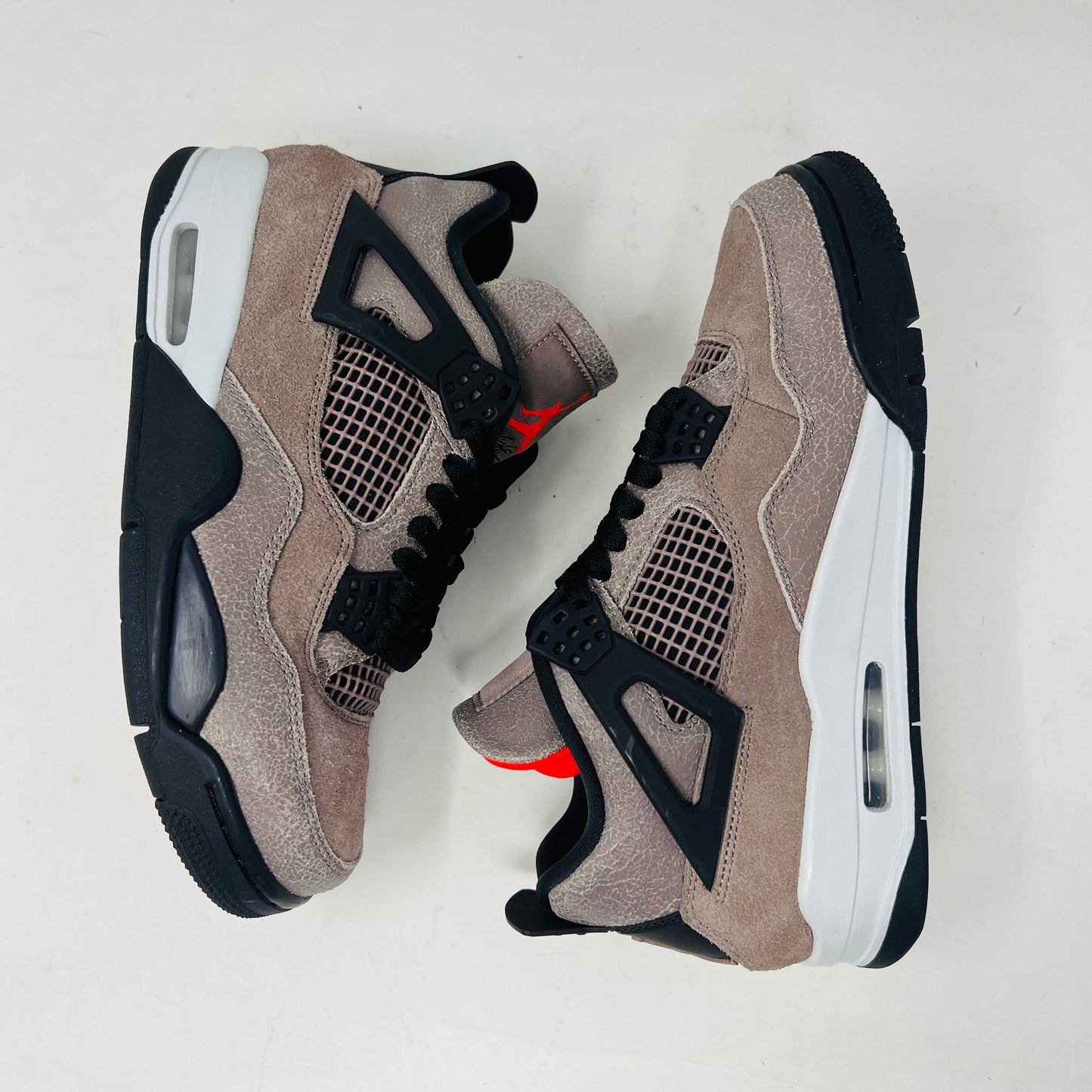 The Jordan 4 Retro Taupe Haze sneaker is showcased on its speckled brown shoebox. Released in 2021, it boasts black mesh accents, a visible air unit, and the Jumpman logo on the tongue. Size and style details are printed on the box.