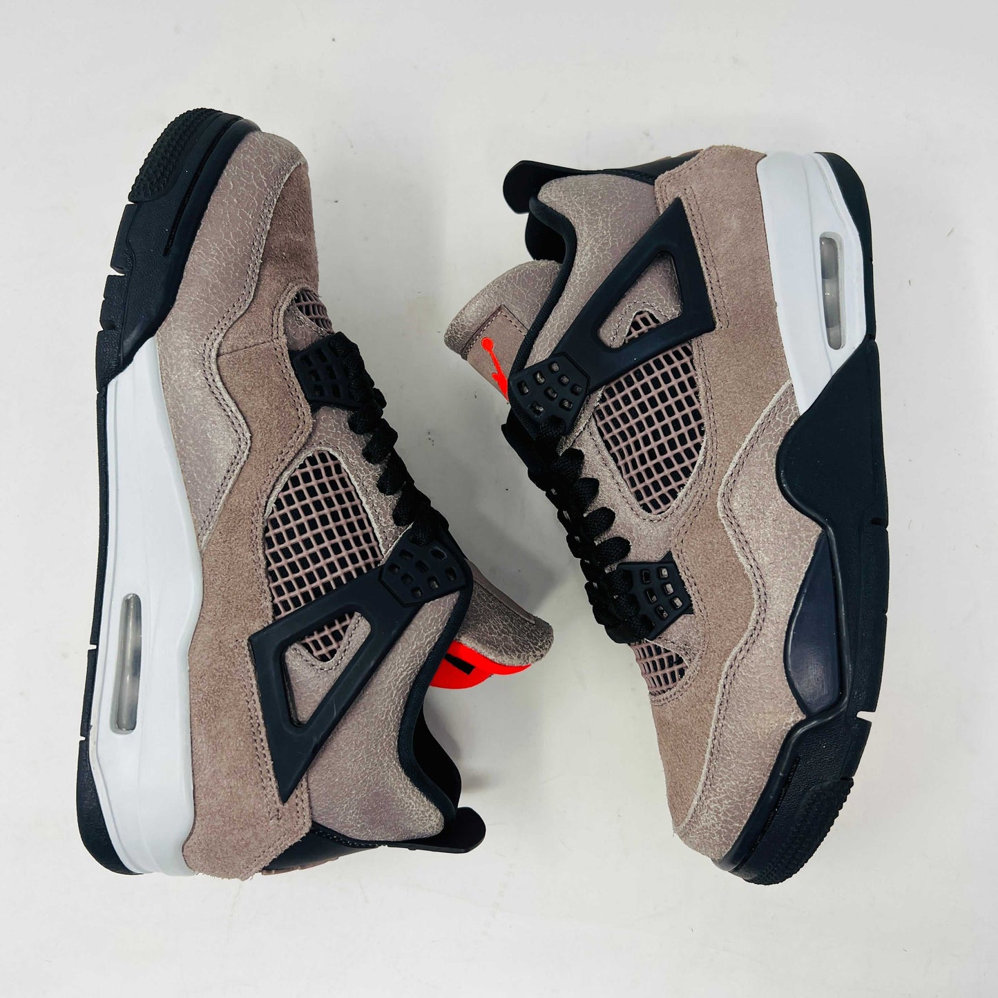 The Jordan 4 Retro Taupe Haze sneaker is showcased on its speckled brown shoebox. Released in 2021, it boasts black mesh accents, a visible air unit, and the Jumpman logo on the tongue. Size and style details are printed on the box.