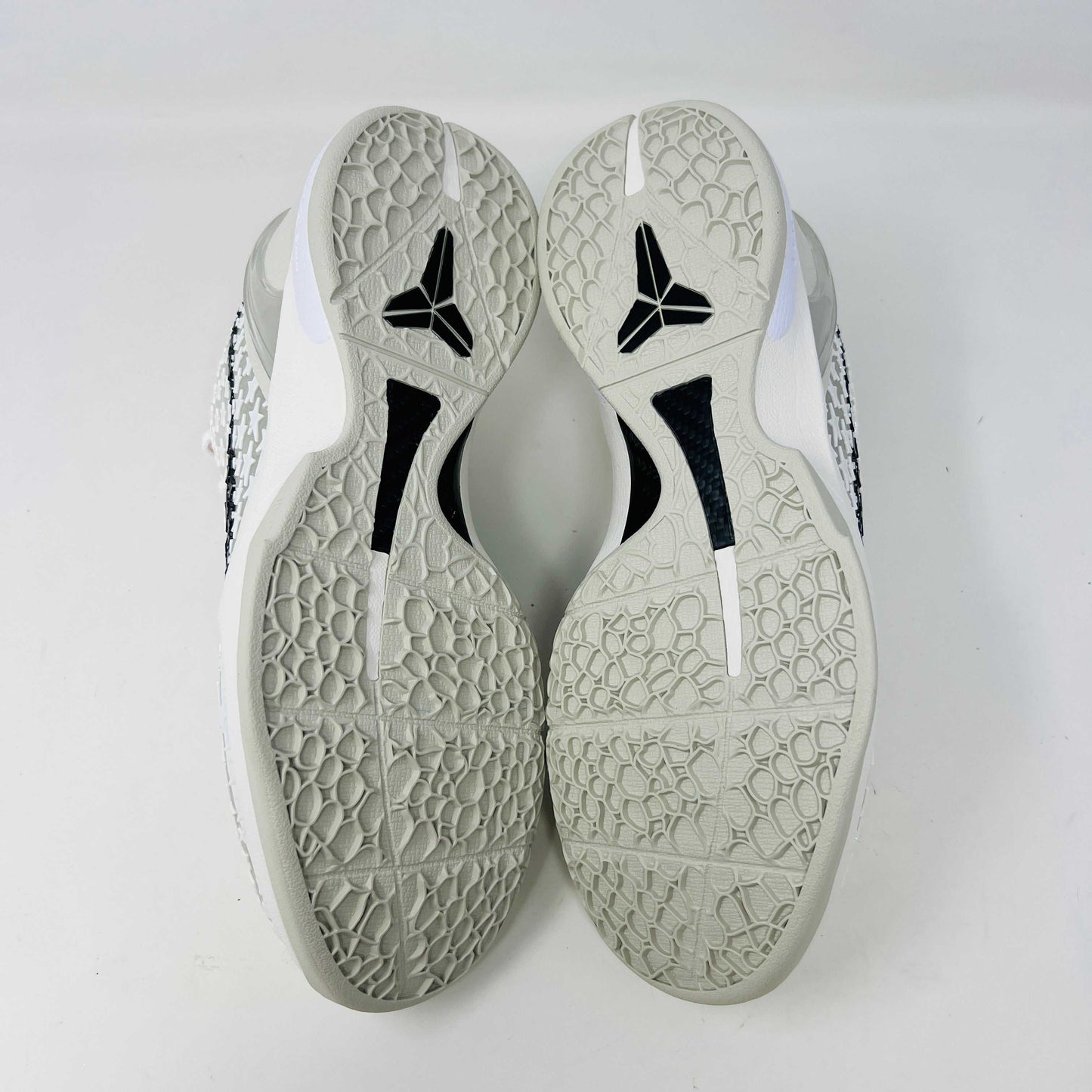 The Nike Kobe 6 Protro Sail All-Star shoes, featuring white textured patterns and black swoosh details with star designs, are elegantly displayed on a sleek black shoebox.