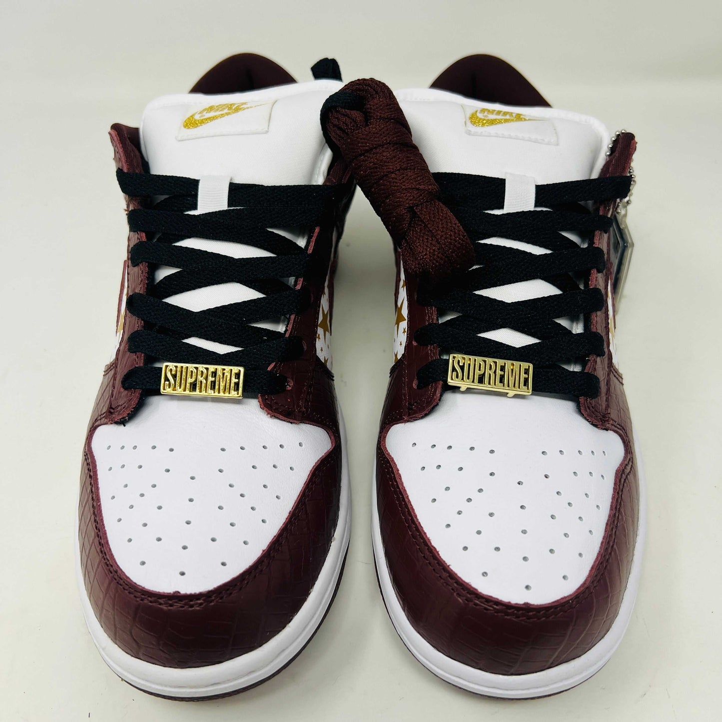 Introducing the new Nike SB Dunk Low Supreme Barkroot sneakers by Nike, featuring a star pattern with a World Famous Supreme tag and housed in a striking purple Nike SB box.