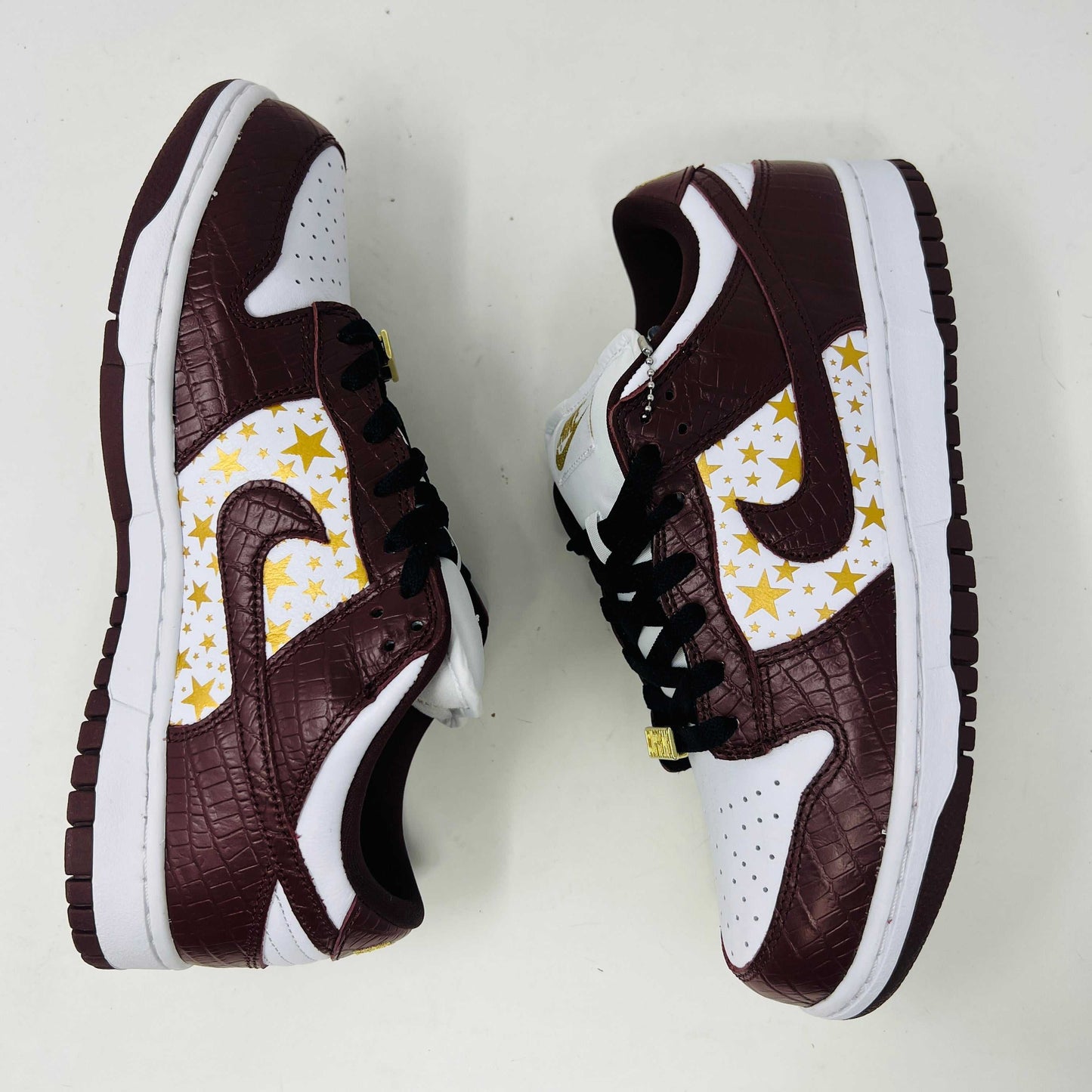 Introducing the new Nike SB Dunk Low Supreme Barkroot sneakers by Nike, featuring a star pattern with a World Famous Supreme tag and housed in a striking purple Nike SB box.