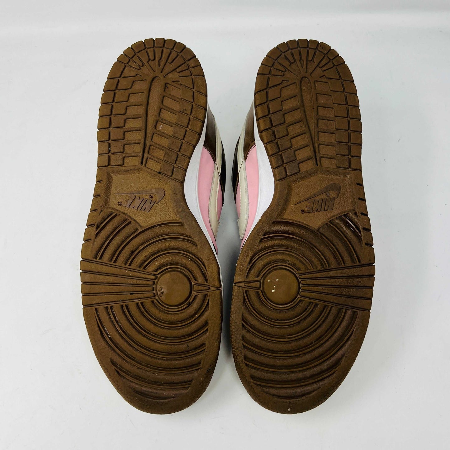 A 2005 Nike SB Dunk Low Stussy Cherry in brown and pink rests on its box, featuring a cream swoosh. The authentic shoe includes extra pink laces in a clear NIKE SB bag. The box label shows size 9.