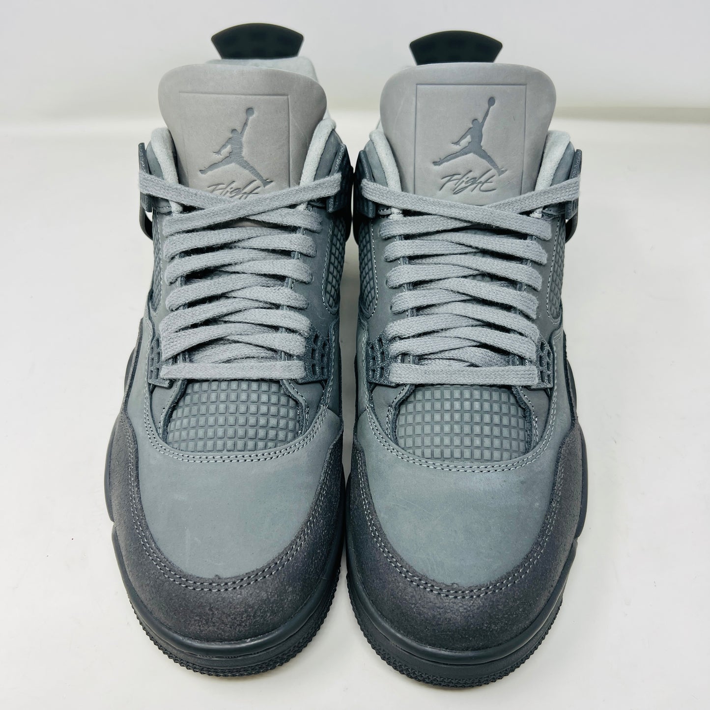 The Jordan 4 Retro SE Paris Olympics Wet Cement sneaker is displayed on its matching gray textured box, showcasing both in pristine condition. It features clean uppers with smooth and mesh textures, a visible air unit, and a size label with US, UK, and EU measurements.