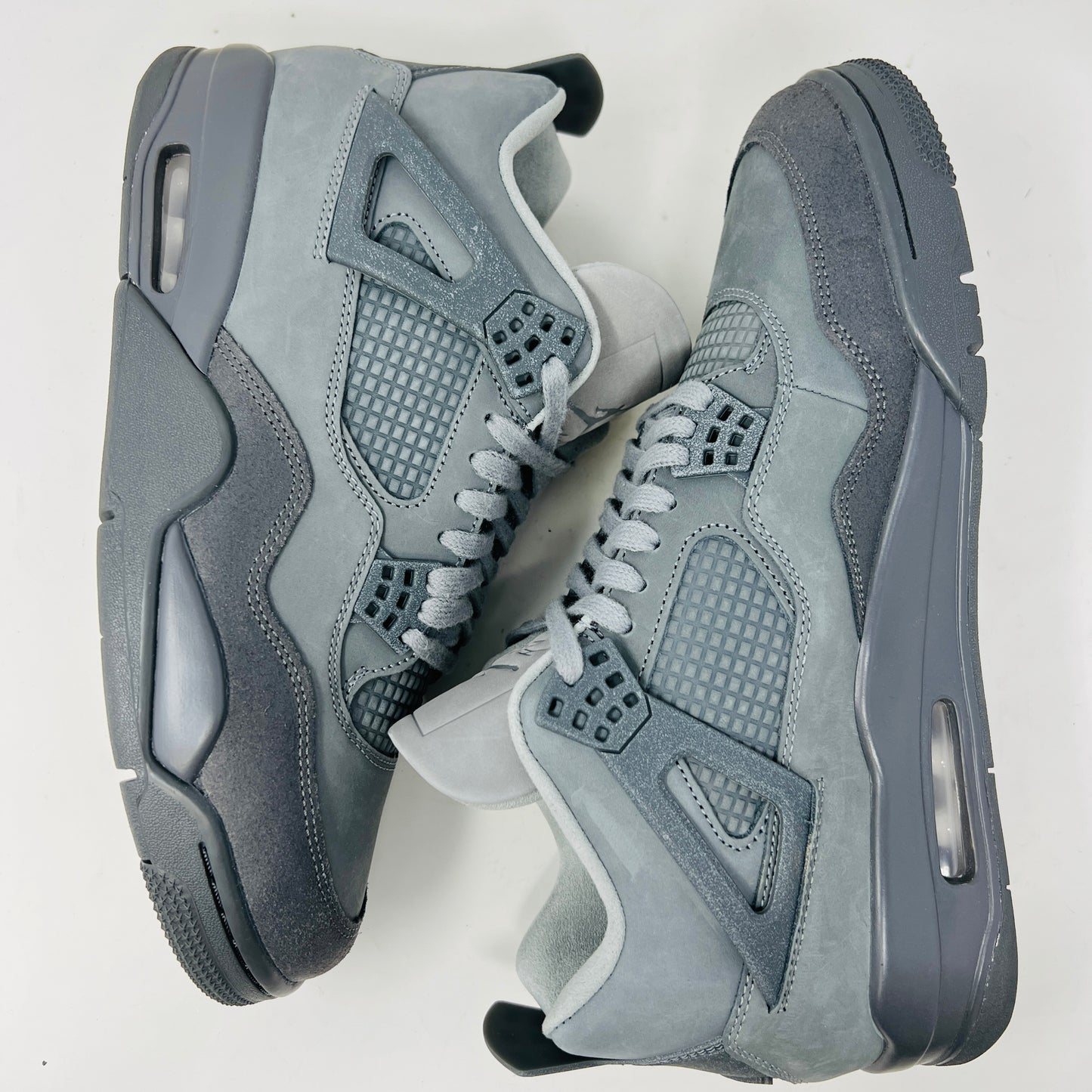 The Jordan 4 Retro SE Paris Olympics Wet Cement sneaker is displayed on its matching gray textured box, showcasing both in pristine condition. It features clean uppers with smooth and mesh textures, a visible air unit, and a size label with US, UK, and EU measurements.