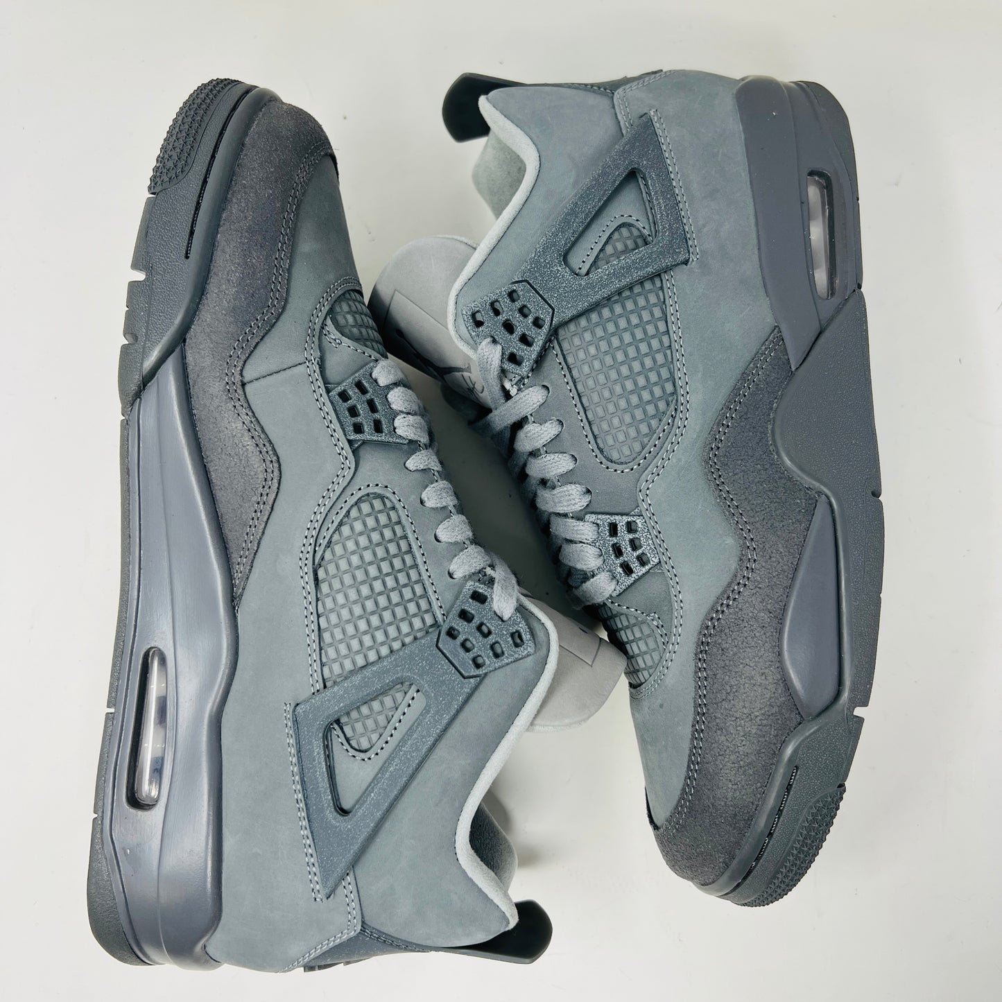 The Jordan 4 Retro SE Paris Olympics Wet Cement sneaker is displayed on its matching gray textured box, showcasing both in pristine condition. It features clean uppers with smooth and mesh textures, a visible air unit, and a size label with US, UK, and EU measurements.