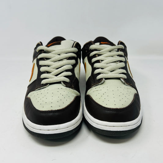 The Nike Dunk Low Pro B Light Stone Mesa Orange sneaker from 2002 is shown side-on, featuring sleek uppers in dark brown and cream with an orange swoosh. It rests elegantly on a white midsole with a black outsole against a plain background.