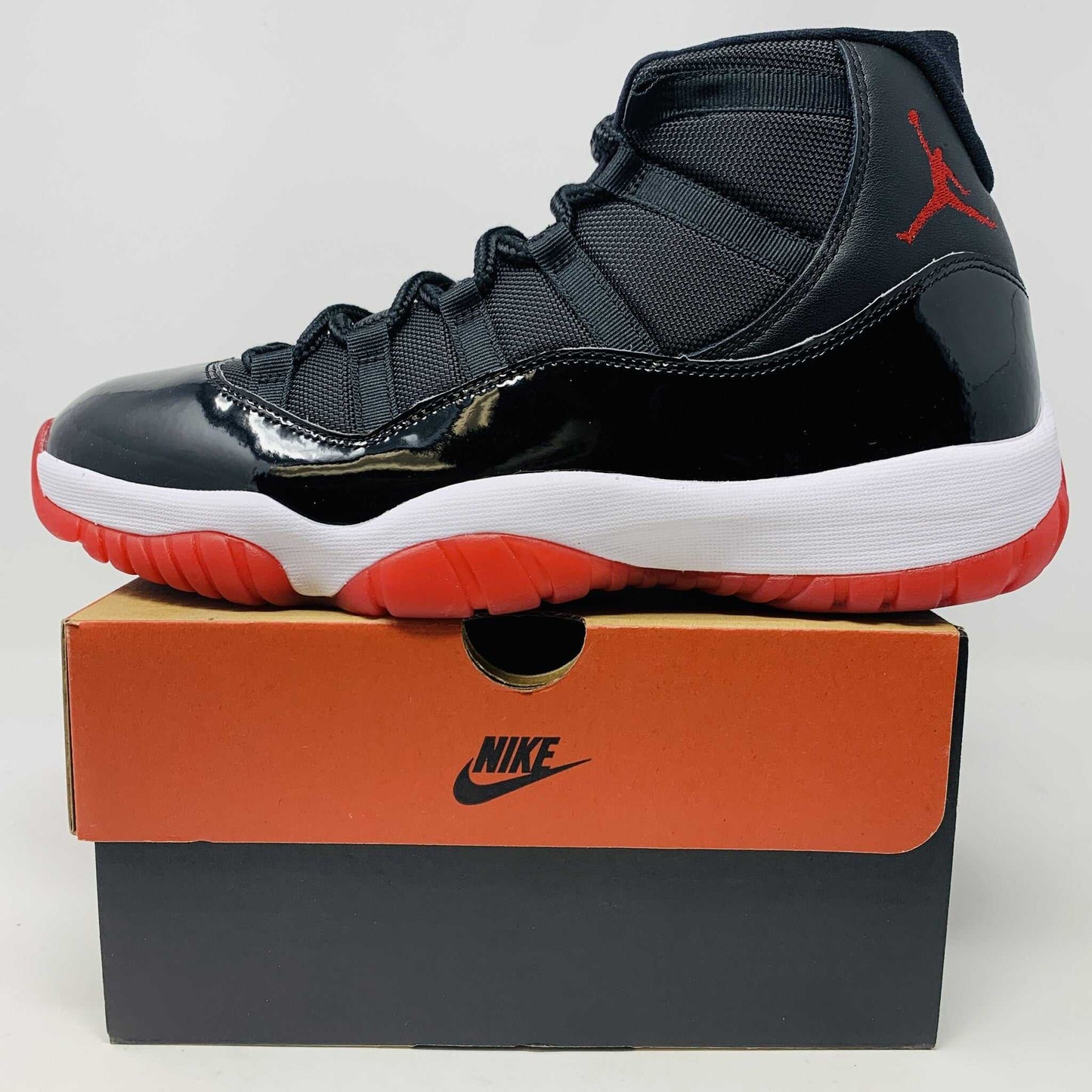 Jordan 11 Bred 2019 sneaker, brand new condition, black and red colorway displayed on Nike box.