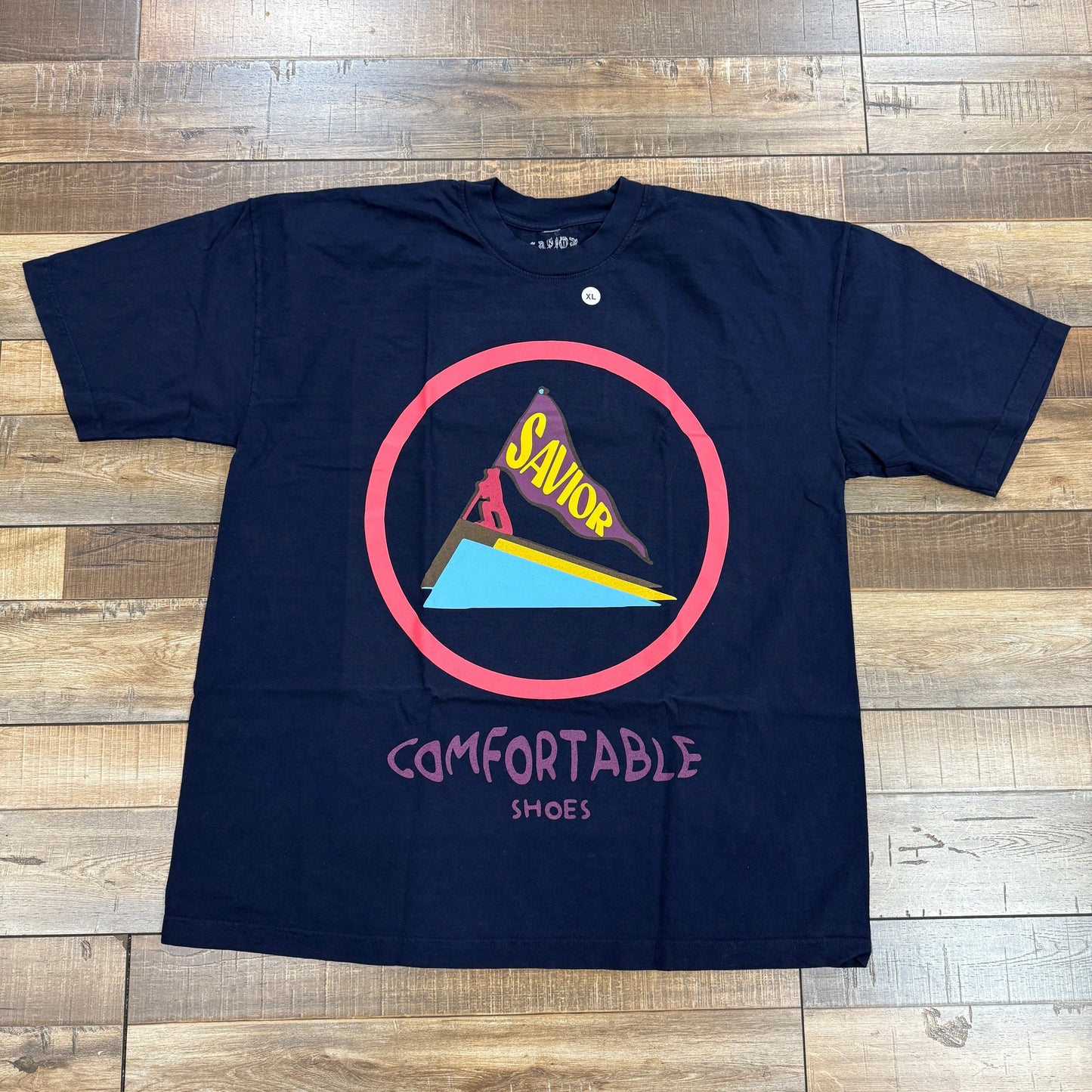 Savior Saucony Tee Navy with graphic design on wooden floor.