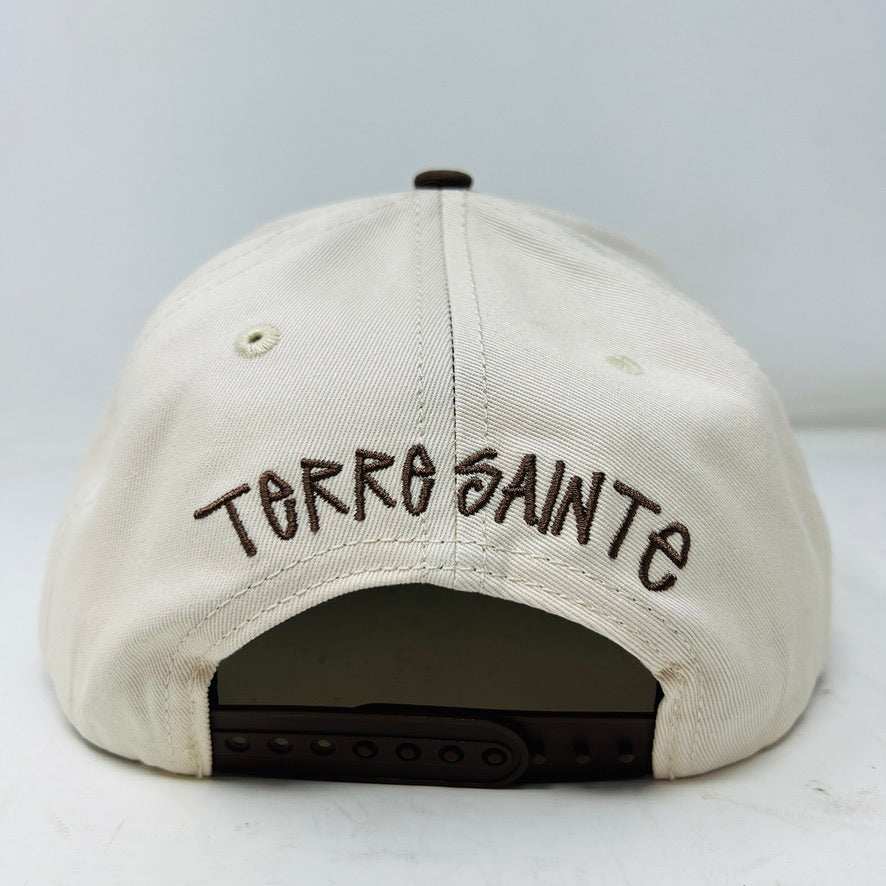 The Holy Ground Stussy Hat by Holy Ground is a streetwear accessory with HOLY GROUND embroidered in black on its white front panel, complemented by a green bill for a fresh touch.