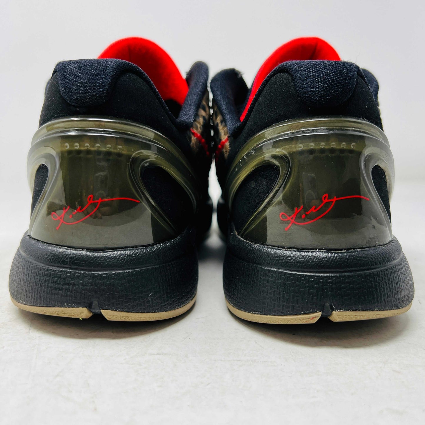 Close-up of a Nike Kobe 6 Protro Italian Camo (2024) (GS) shoe in black and dark olive with a red swoosh, resting on an orange Nike box. The 100% authentic shoe features a textured upper shown from the side, highlighting its design and striking color contrast.