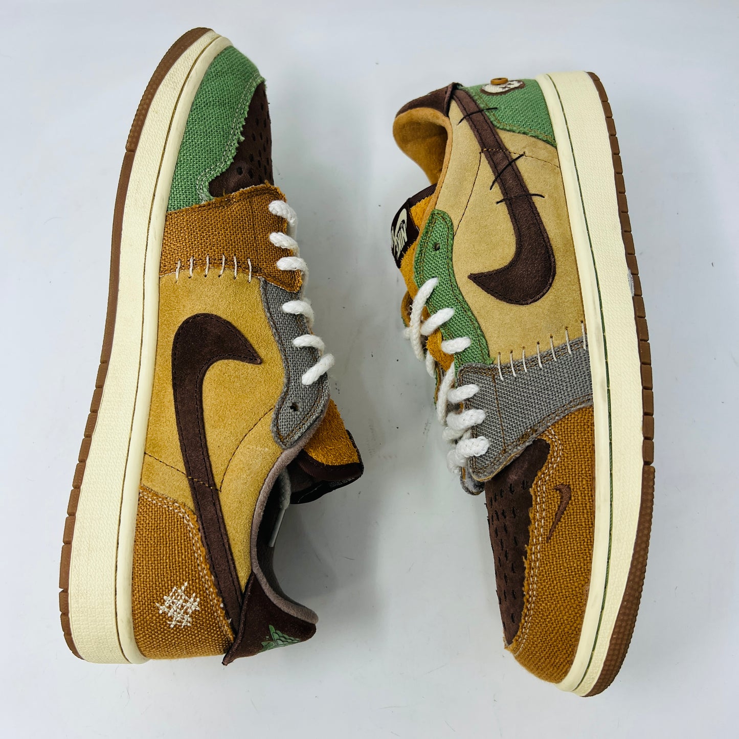 Multicolored Jordan 1 Retro Low OG Zion Williamson Voodoo sneakers feature a patchwork design and visible stitching with brown, yellow, and green sections. The stylish kicks have clean uppers with minimal heel drag, set elegantly on a purple box displaying size and price labels.