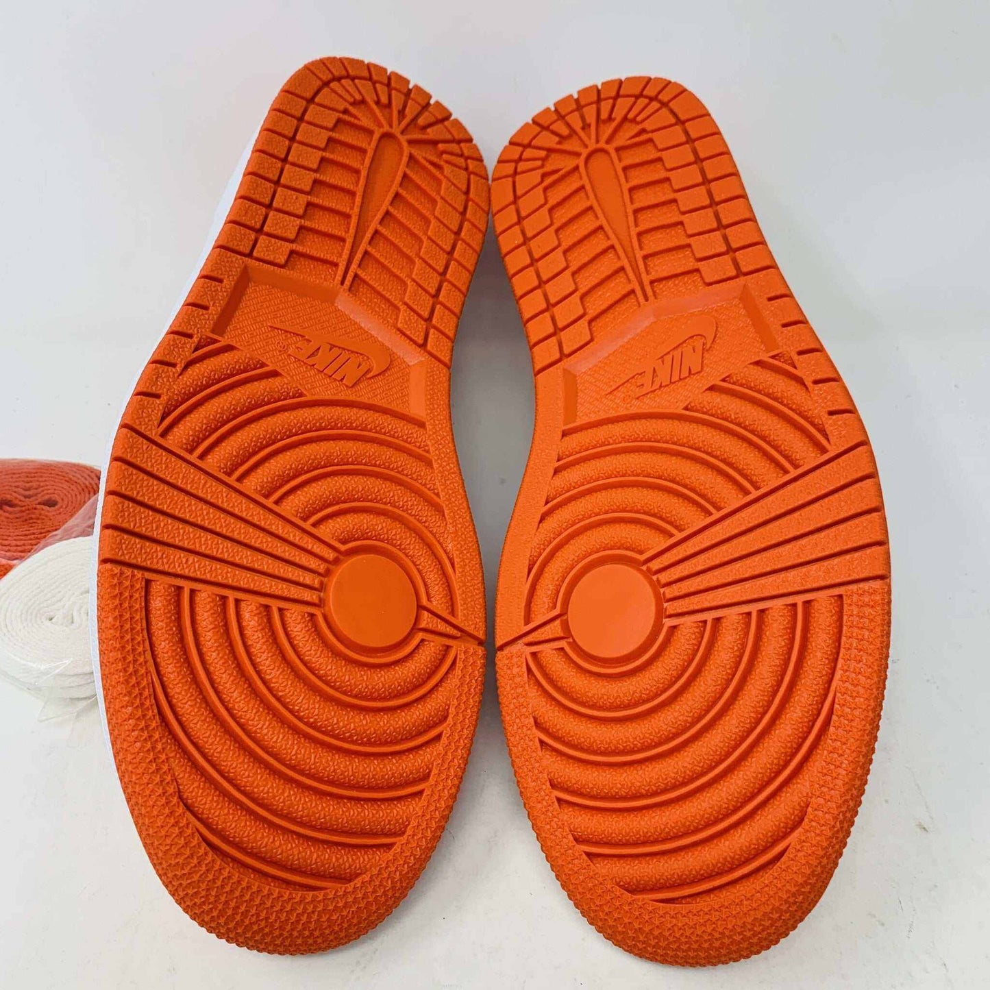 A pair of BRAND NEW Jordan 1 Low Starfish sneakers is displayed, viewed from the front. The orange and white shoes have black laces, a perforated white toe box, and the 100% Authentic Jordan logo is visible on the tongue.