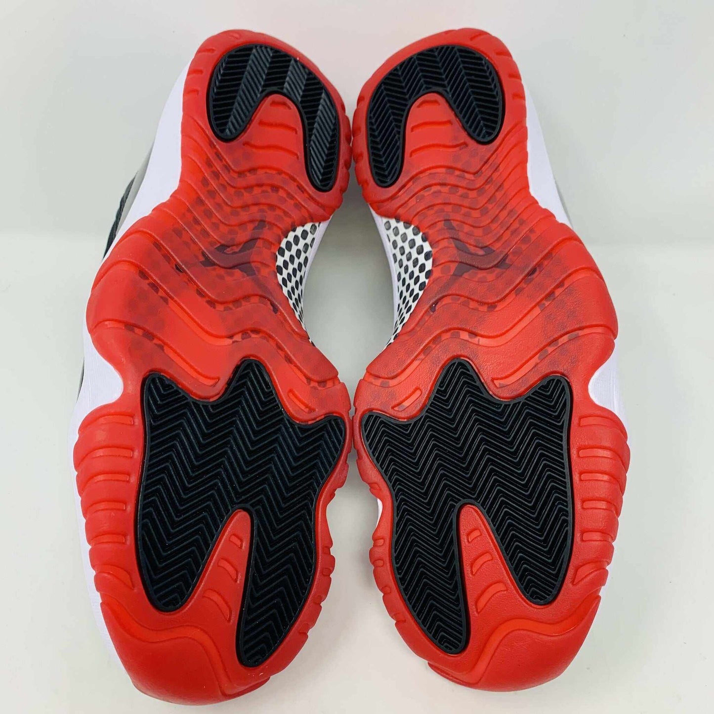The brand new Jordan 11 Bred 2019 features a black and red high-top design with glossy accents, striking red soles, and a bold red Jumpman logo. It sits atop an orange and black Nike shoebox, exuding style and performance.