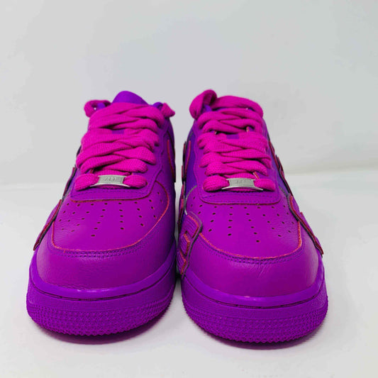 The Nike Air Force 1 Low Cactus Plant Flea Market Fuchsia Dream sneaker, vibrant pink with oversized SUN lettering, boldly sits on a black box featuring the iconic white swoosh. This brand new, 100% authentic pair includes extra laces and is presented against a plain white background.