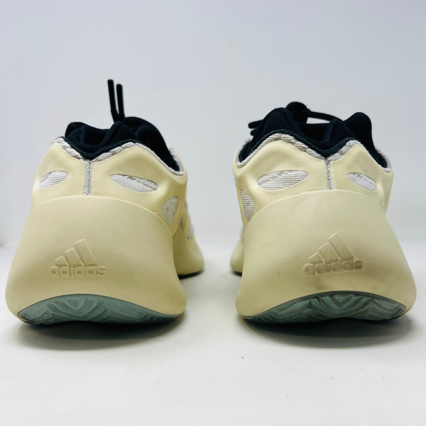 The adidas Yeezy 700 V3 Azael features a futuristic design with a black mesh upper, white and beige sculpted overlays, and an intricate lacing system. It has a sleek, modern look set against a plain white background, showing minimal wear for that fresh out-of-the-box condition.