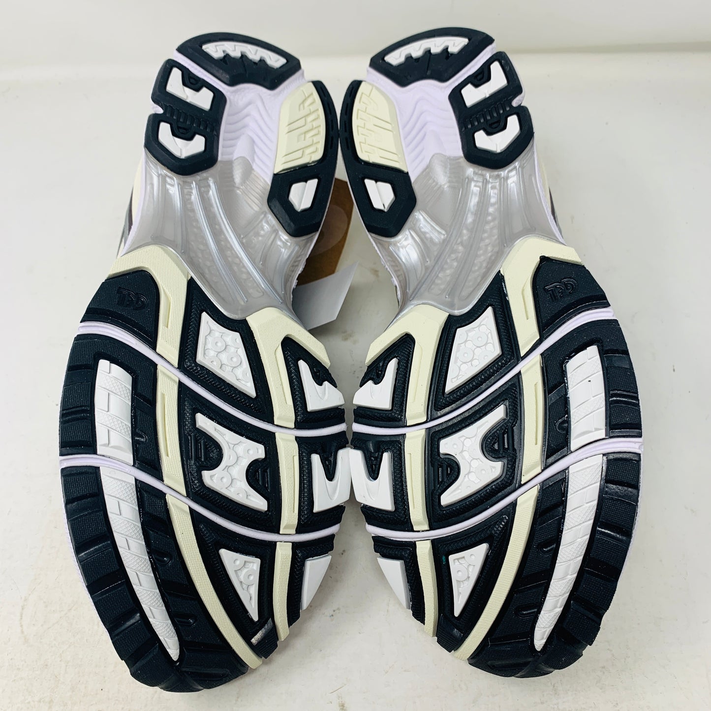 Brand new ASICS Gel-Kayano 14 Cream Black Metallic Plum sneakers rest elegantly on a pristine brown ASICS shoe box. With a mesh upper, metallic accents, and black details, these shoes stand out against a neutral backdrop.