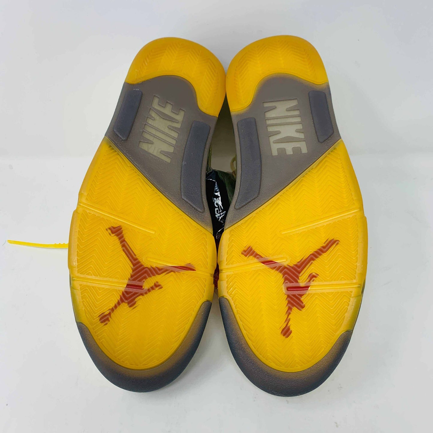 The Jordan 5 Off White Sail sneakers feature a yellow and black design with red accents, a visible air unit, and the number 23 on the side. BRAND NEW in a black shoebox with a red Jumpman logo and speckled base, they include an attached yellow tag and come with EXTRA LACES for versatility.