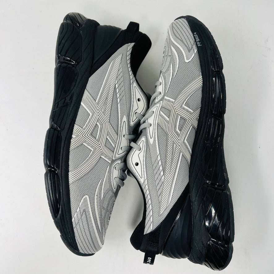 A side view of the ASICS Gel-Quantum 360 VIII C.P. Company in Cement Grey, featuring a sleek modern design with gray and silver elements, black accents, a black sole, and subtle patterns on its clean upper. The background is plain white.