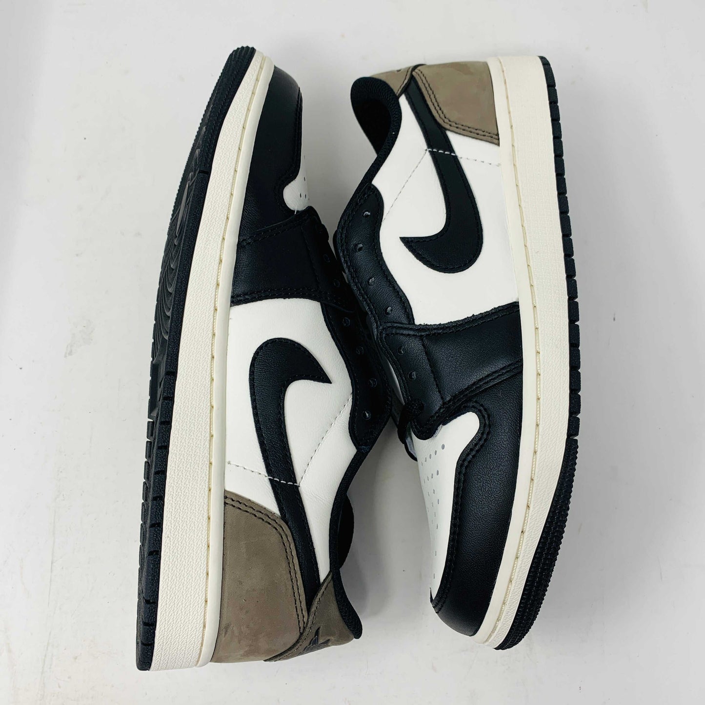 The Jordan 1 Retro Low OG Mocha sneakers, positioned laterally against a plain white background, exhibit a black and white color scheme with brown accents and a black swoosh logo. This 2024 release from Jordan ensures style and quality in good box condition.