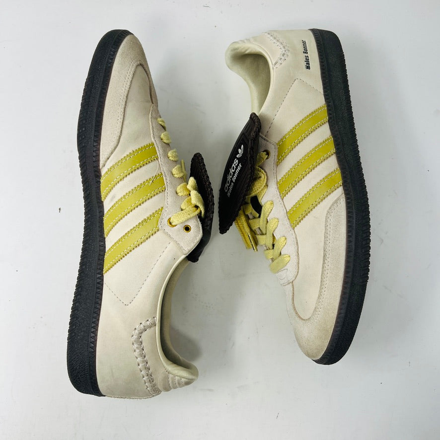 The 2023 adidas Samba Wales Bonner Ecrtin Brown sneakers feature beige uppers with three yellow stripes, a brown logo flap, and black soles. Despite general wear, the side and tongue branding stays distinct. Theyre displayed side by side on a white background.