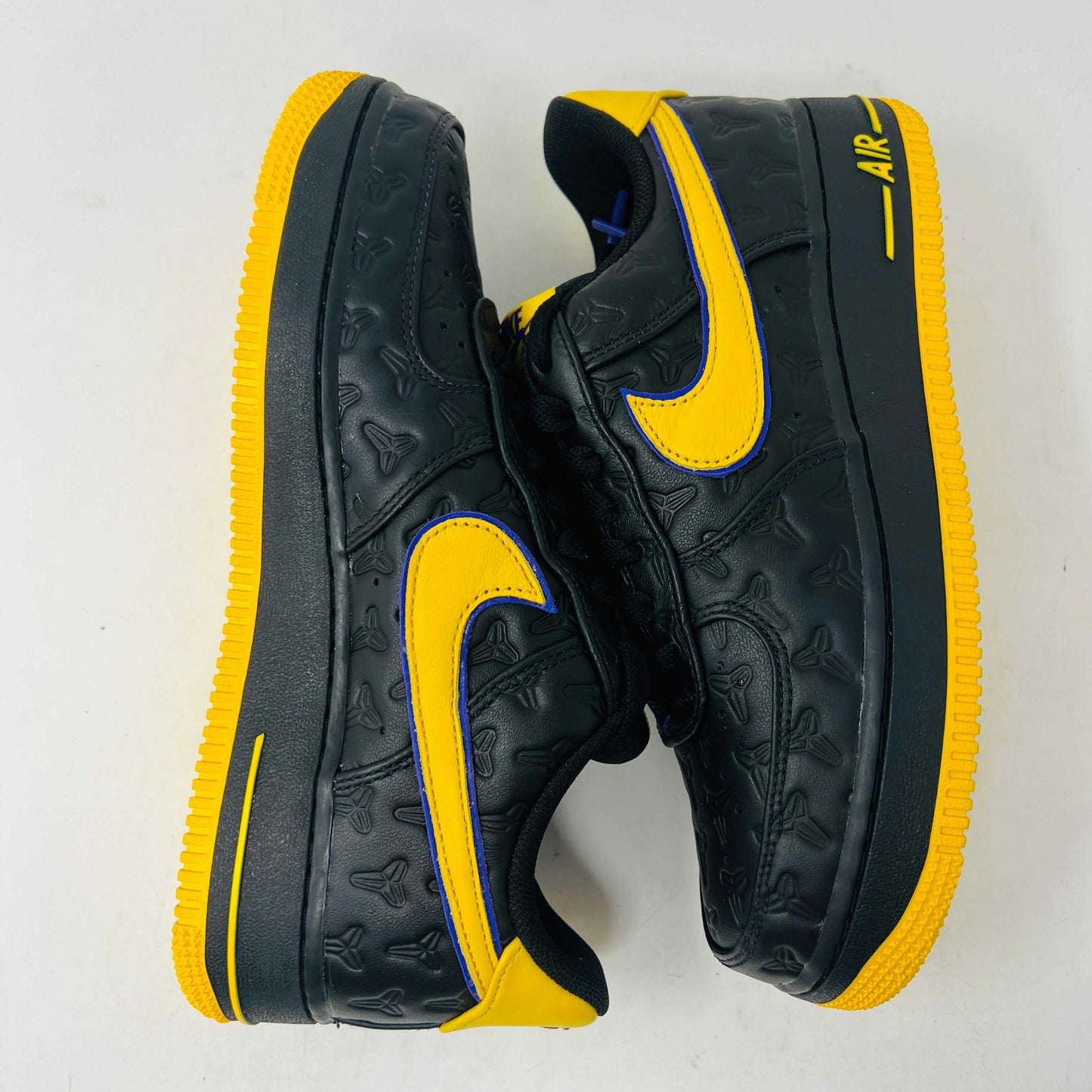 The new black Nike Air Force 1 Low Kobe Bryant Lakers Away sneakers have yellow accents like a swoosh and sole, sitting on a white box with the Nike logo and icon. These 100% authentic shoes are available as a final sale item.