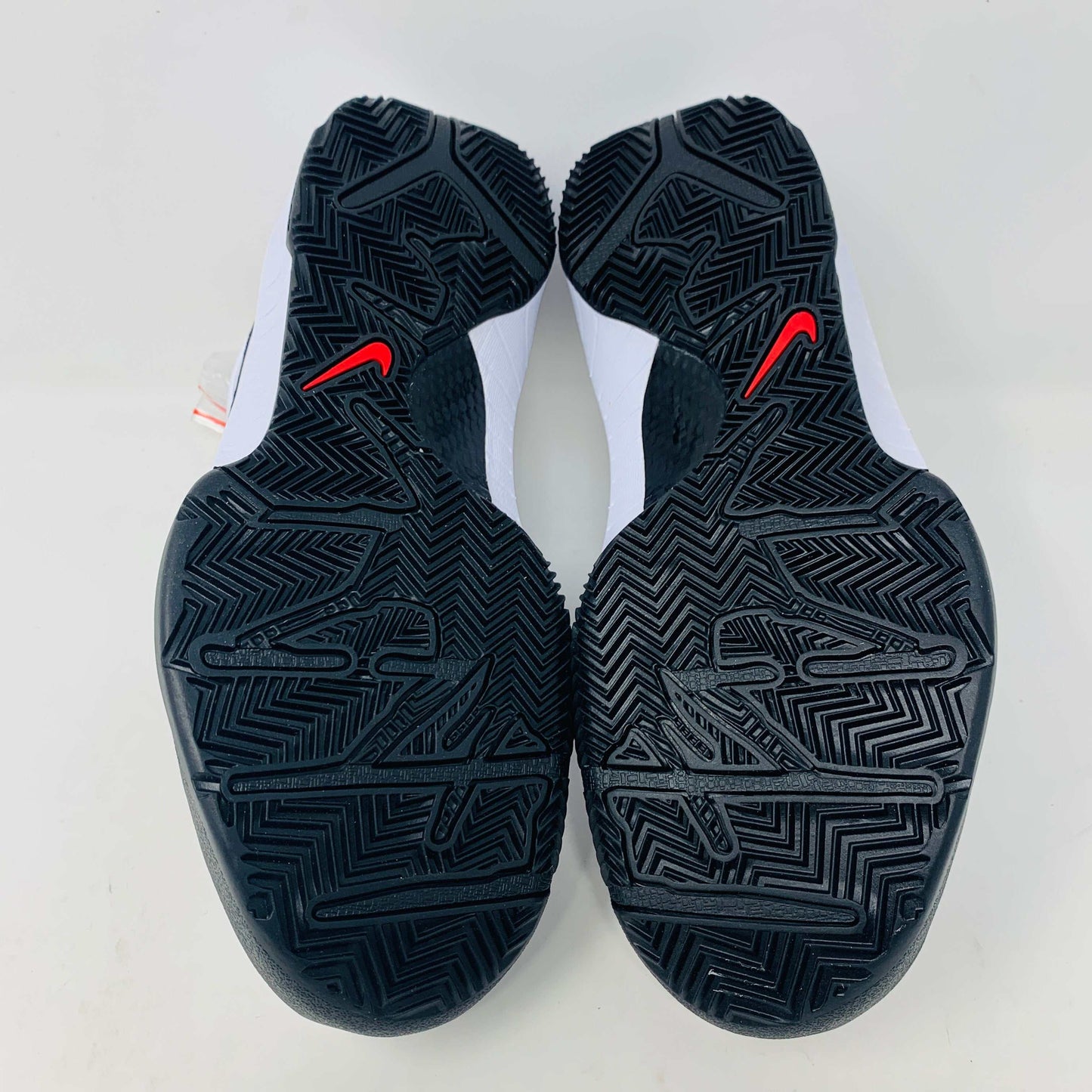 The Nike Kobe 4 Protro Mambacita Gigi shoe, featuring a black swoosh, black accents, and a checkered heel pattern, is displayed on a white box with a gold Nike logo. The box also includes extra laces.