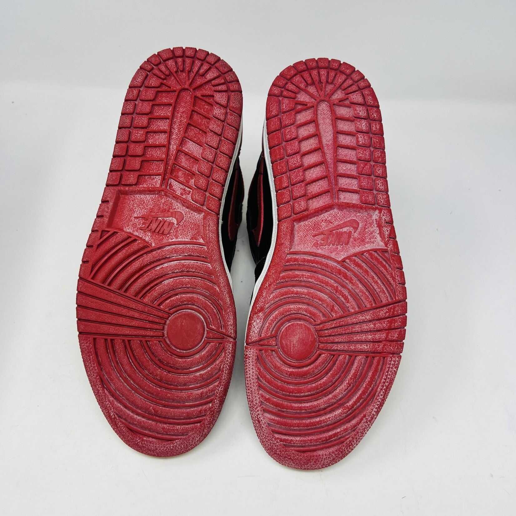 A pair of brand new Jordan 1 Retro Bred (1994) sneakers is displayed on a box, featuring the iconic Nike swoosh and wings logo. A black-and-white photo of the shoes is behind them. The box has various sneaker-related graphics, emphasizing their authenticity.