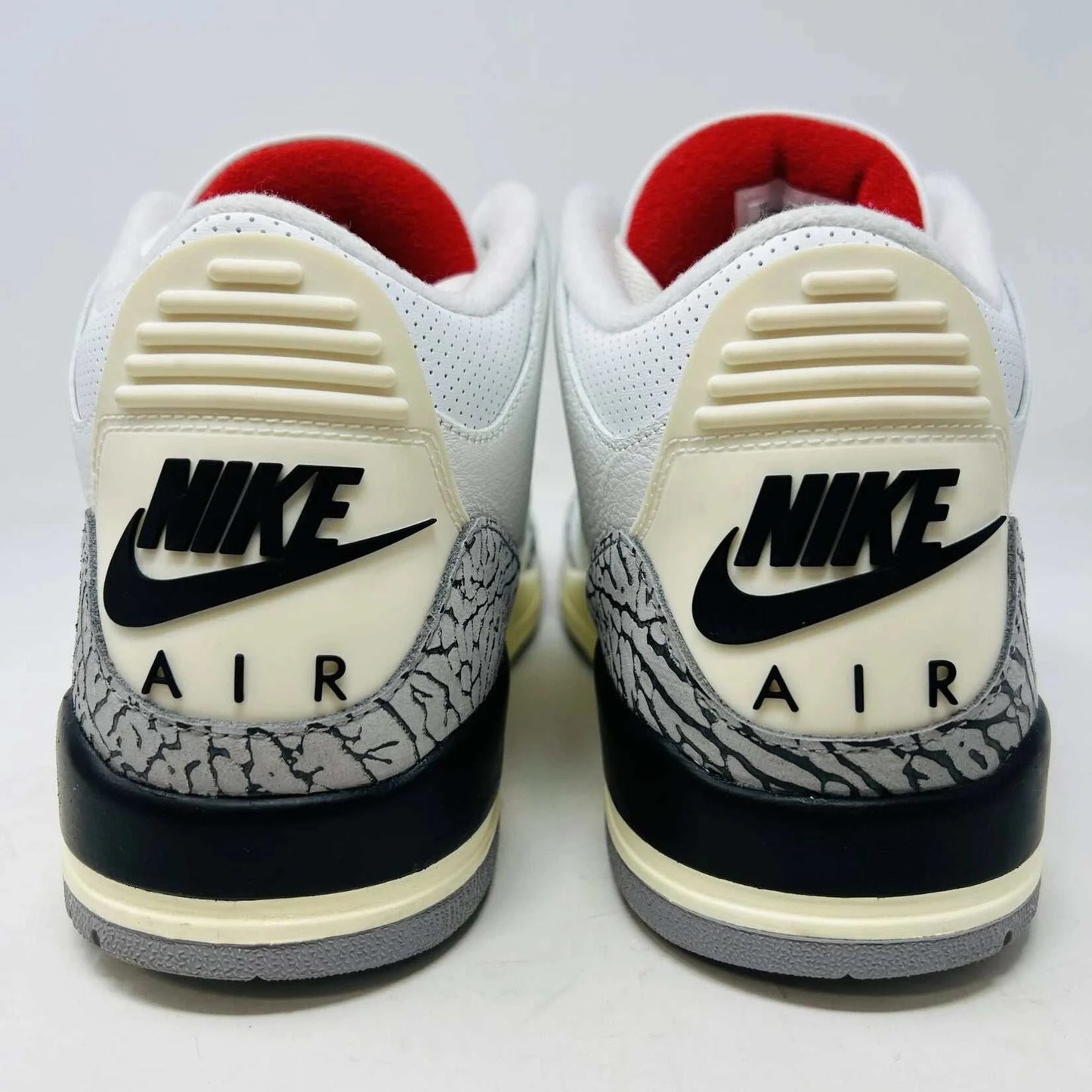 The Jordan 3 Retro White Cement Reimagined sneaker, size 13, features authentic quality with elephant print accents, black and red details, and a visible air unit. It comes in a matching Nike Air shoebox highlighting branding details.