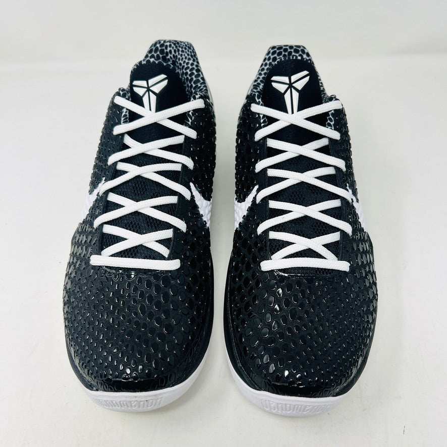 The KOBE Nike Kobe 6 Protro Mambacita Sweet 16 shoe, featuring clean black and white uppers, a white Swoosh, and a small gold 2 on the heel, is displayed on top of its black box with a Nike label. A sealed bag containing black laces accompanies the box for an authentic presentation.