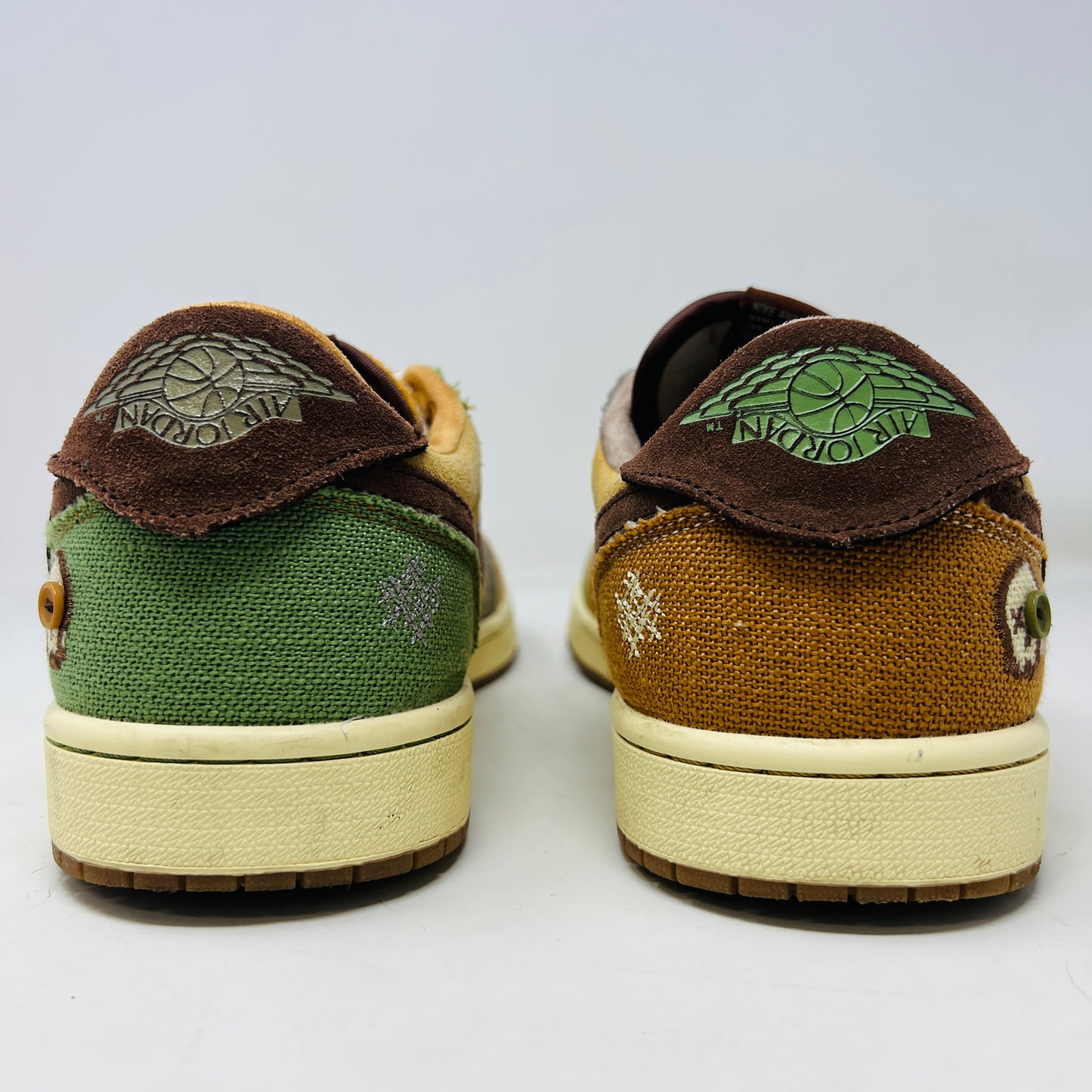 Multicolored Jordan 1 Retro Low OG Zion Williamson Voodoo sneakers feature a patchwork design and visible stitching with brown, yellow, and green sections. The stylish kicks have clean uppers with minimal heel drag, set elegantly on a purple box displaying size and price labels.