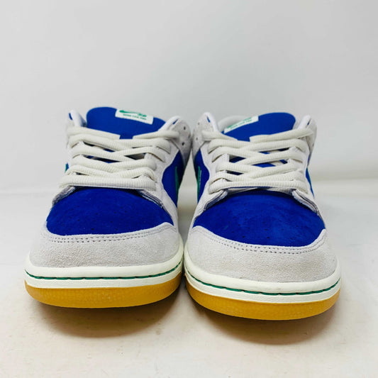 The Nike SB Dunk Low Hyper Royal Malachite, a fresh pair of white and blue sneakers with a green swoosh and gum sole, includes extra laces and is presented atop a purple Nike SB shoe box.