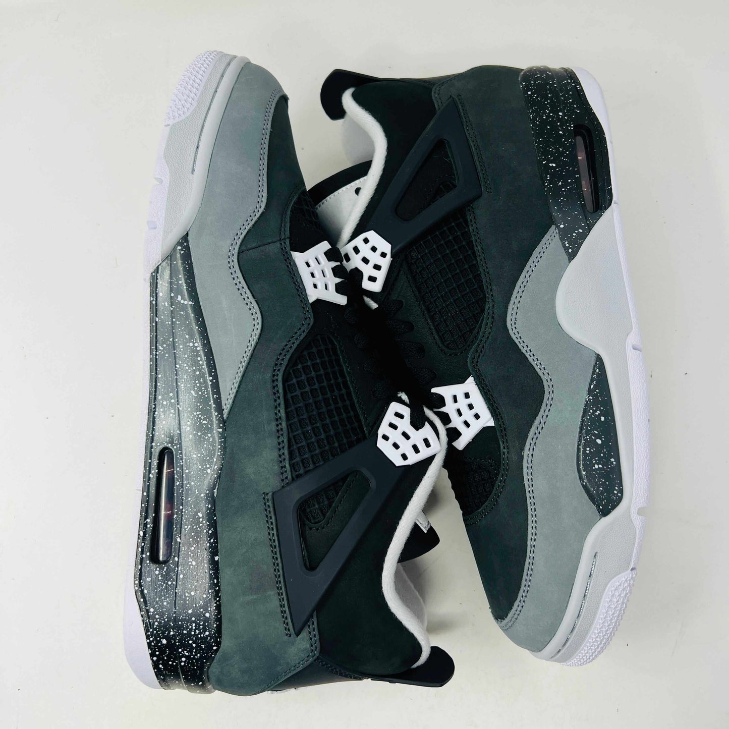 On top of a shoebox sits the brand-new Jordan 4 Retro Fear (2024), a stylish sneaker by Jordan. Its black and gray color scheme, black mesh accents, white midsole, and speckled heel details make it a must-have for 2024.
