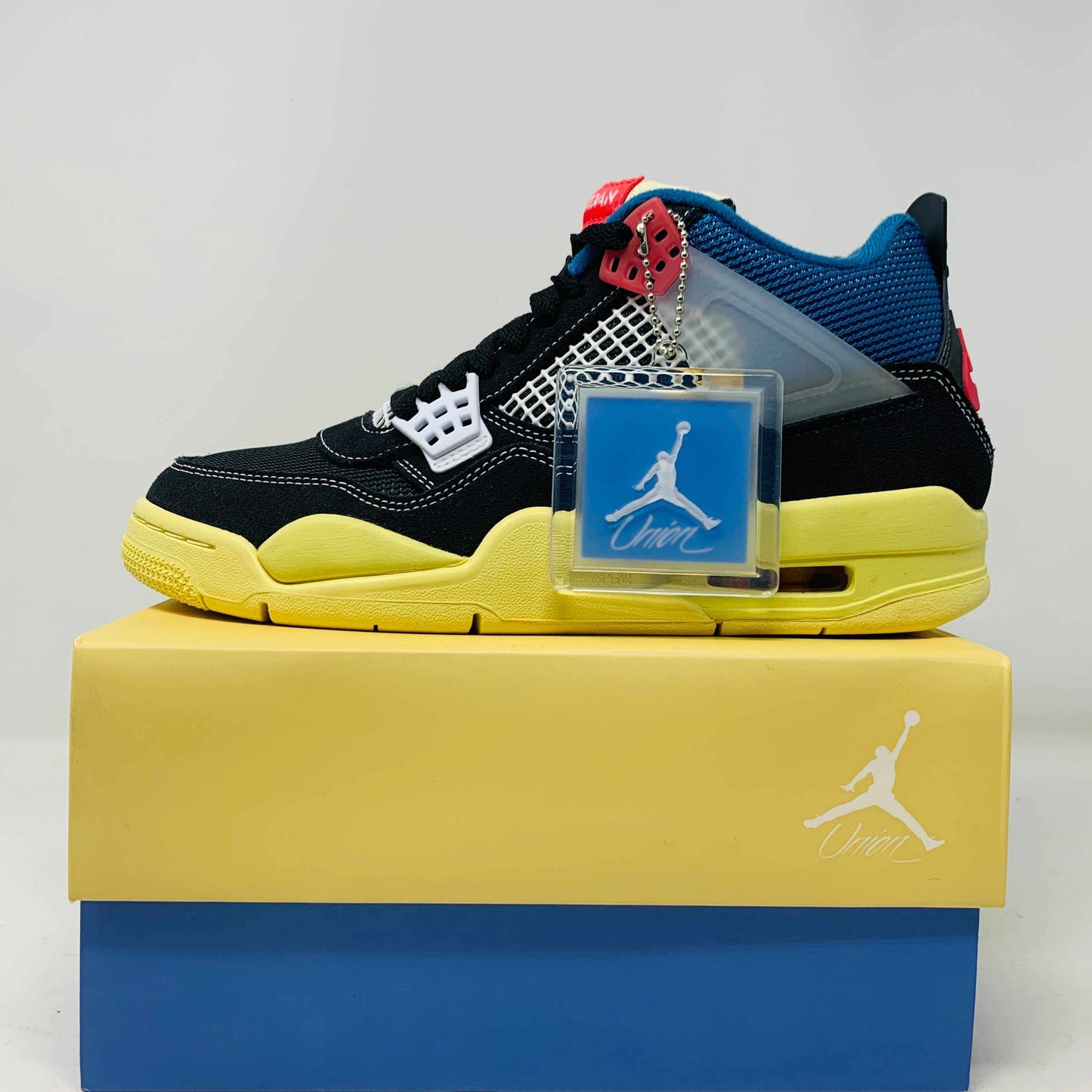Jordan 4 Union sneaker in black and yellow with blue accents on original box and extra laces tag