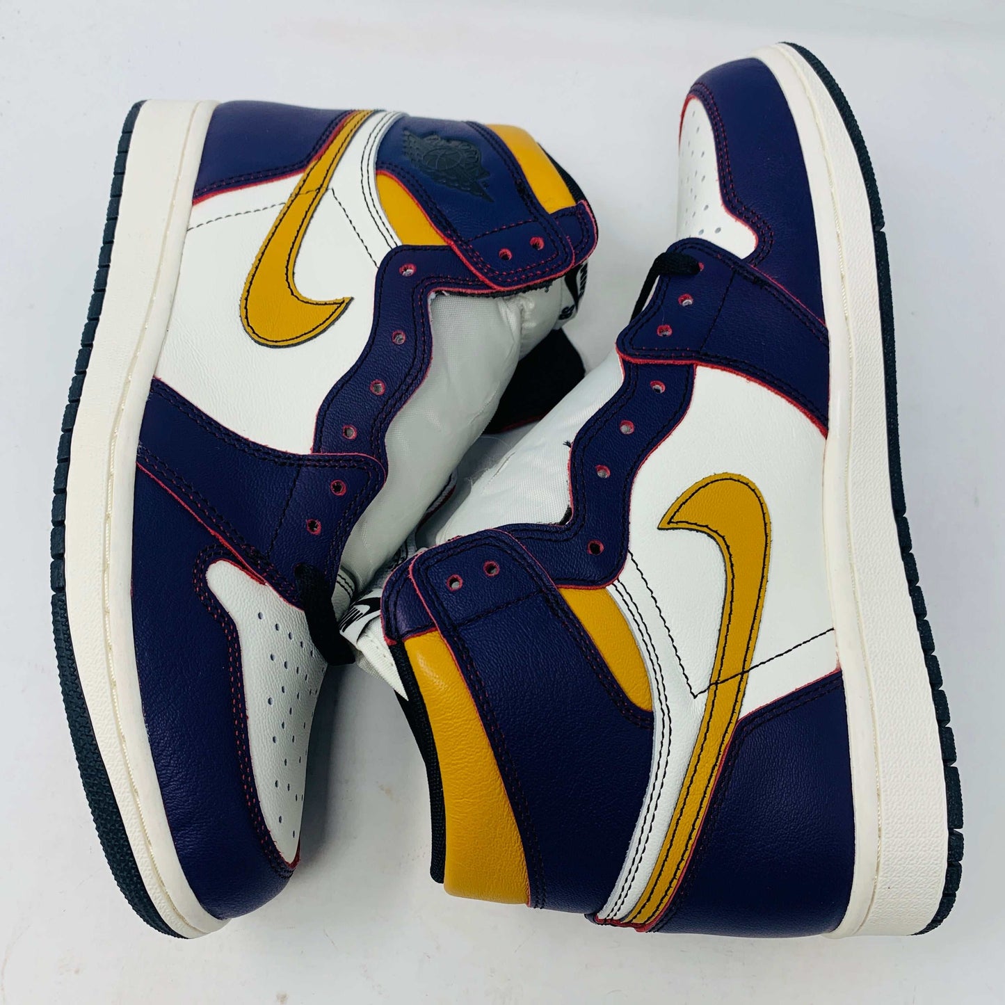 A brand new Jordan 1 High SB LA to Chi sneaker rests on a black Jordan box with a red logo. This authentic high-top shoe features multi-colored accents of purple, yellow, white, and red, with the label proudly reading 1985 Air Jordan 1.