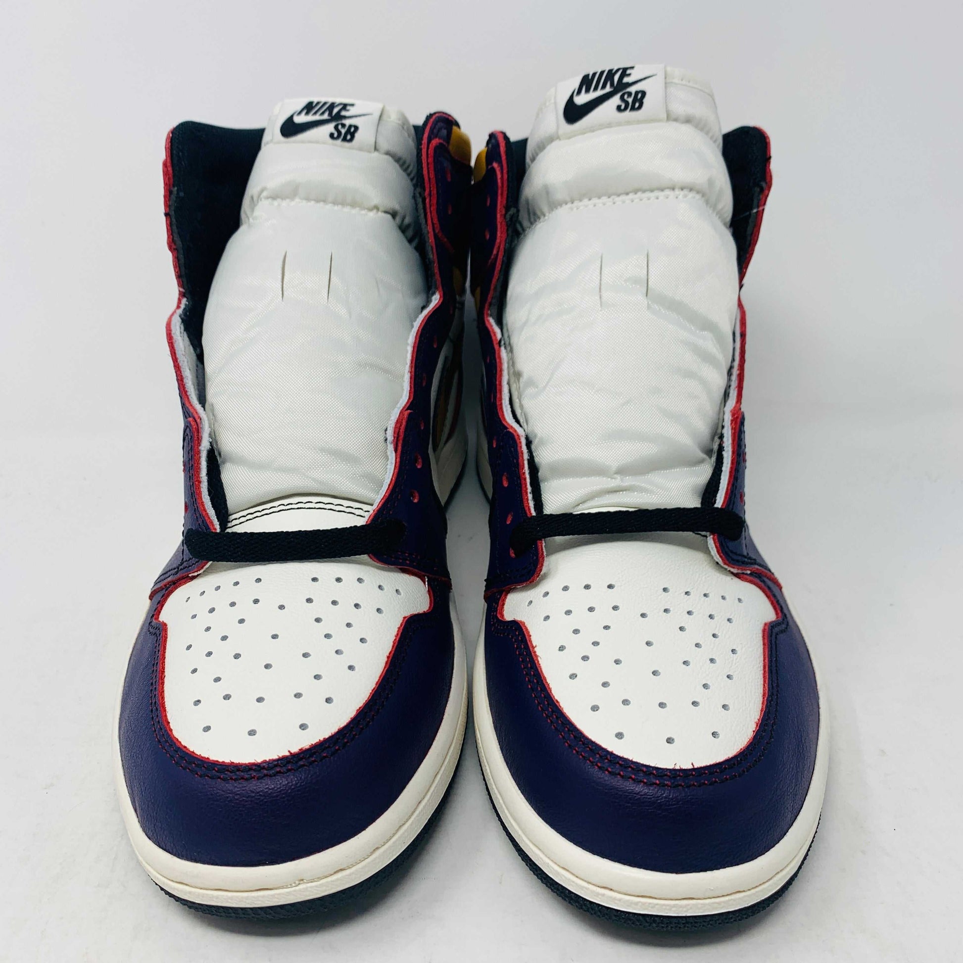 A brand new Jordan 1 High SB LA to Chi sneaker rests on a black Jordan box with a red logo. This authentic high-top shoe features multi-colored accents of purple, yellow, white, and red, with the label proudly reading 1985 Air Jordan 1.