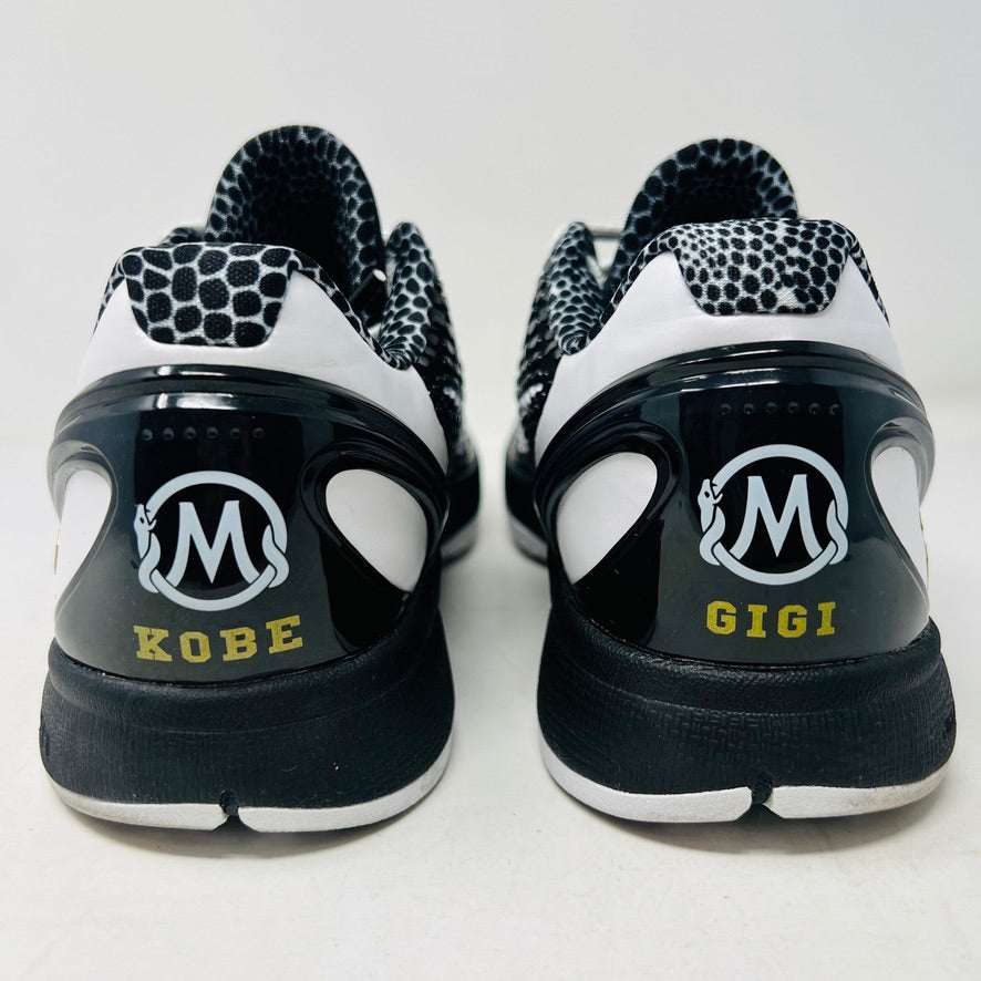 The KOBE Nike Kobe 6 Protro Mambacita Sweet 16 shoe, featuring clean black and white uppers, a white Swoosh, and a small gold 2 on the heel, is displayed on top of its black box with a Nike label. A sealed bag containing black laces accompanies the box for an authentic presentation.