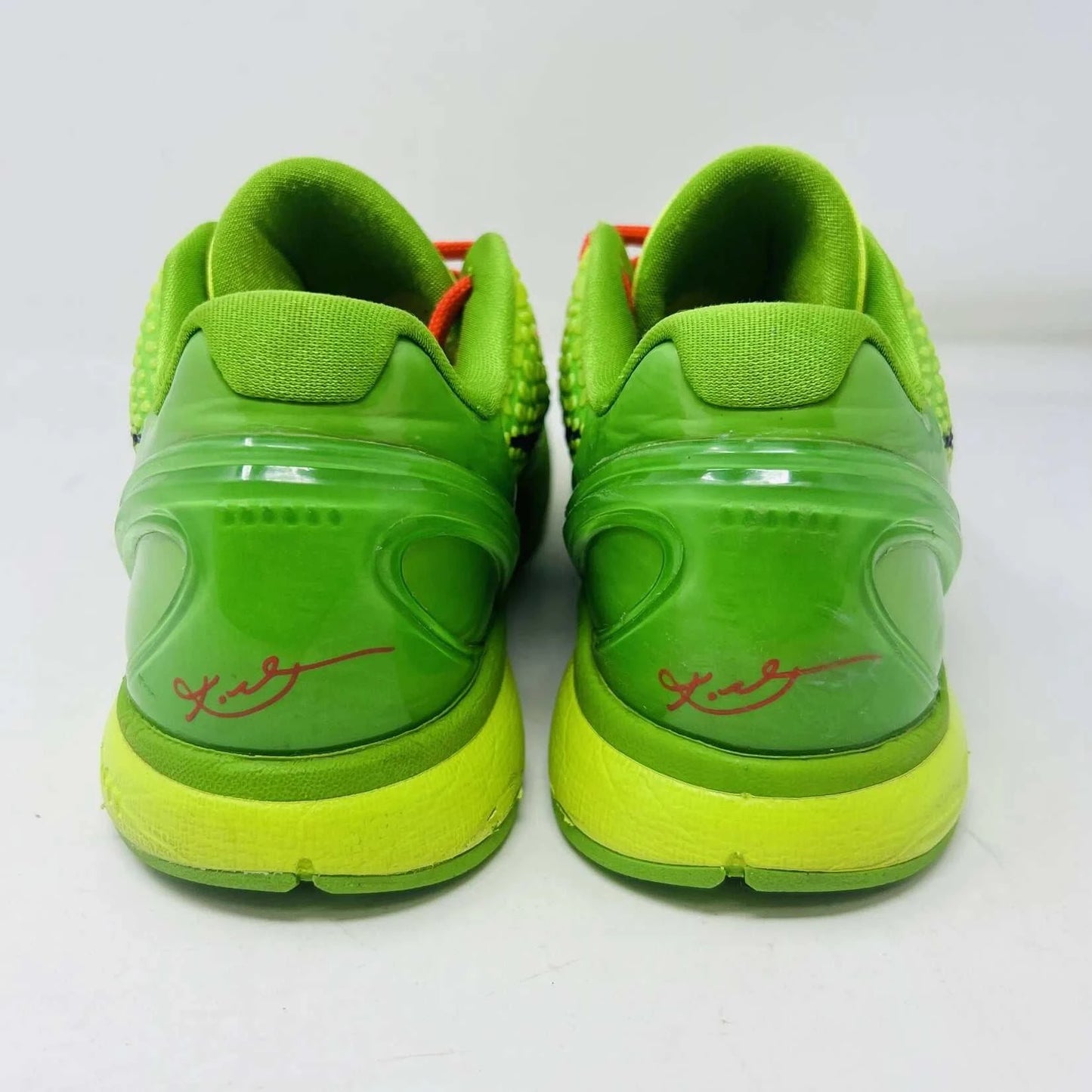 The Nike Kobe 6 Protro Grinch (2020) sports shoes are bright green with a textured surface, red laces, and feature the iconic black Nike swoosh logo. Zoom Air technology is indicated on their side. They are presented against a plain background.